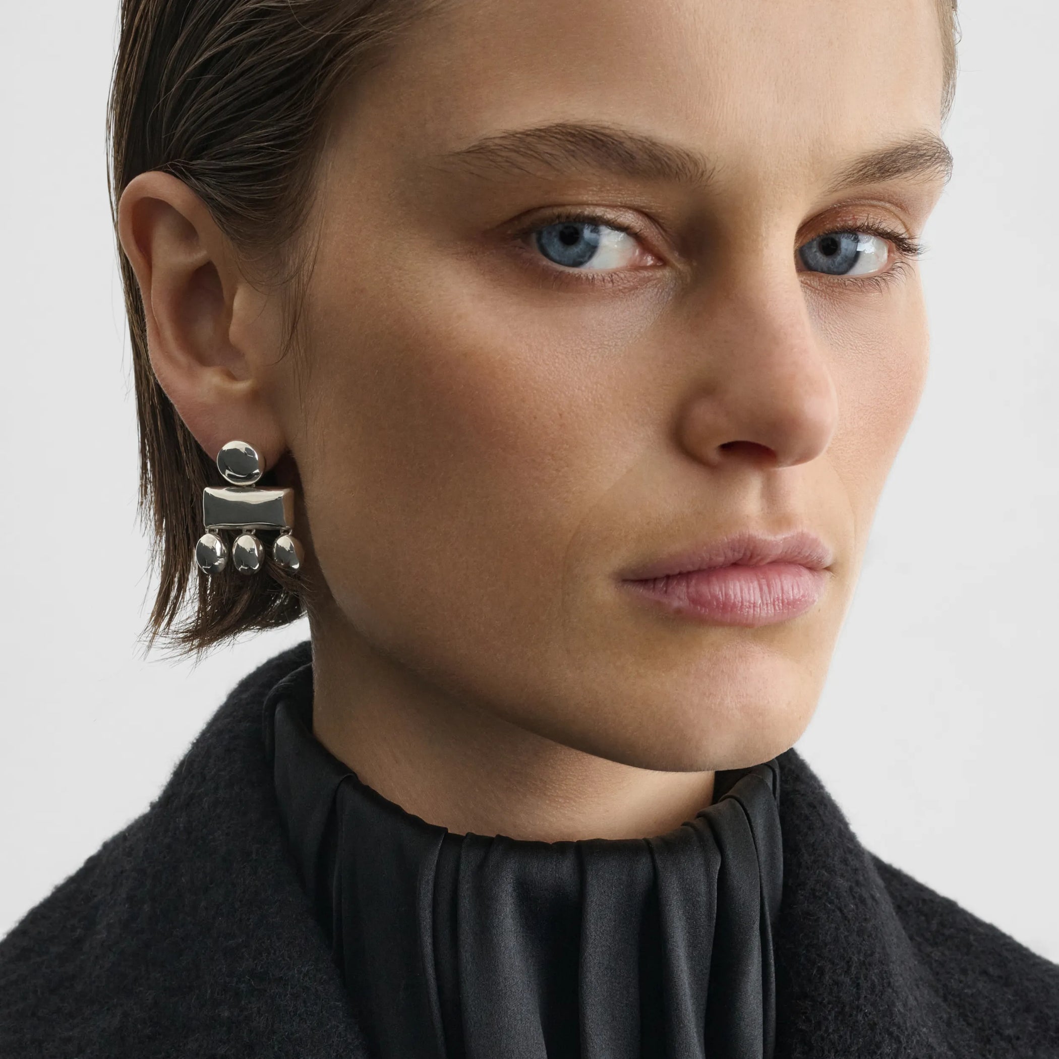 Front view of model wearing mini chandelier earrings in sterling silver.