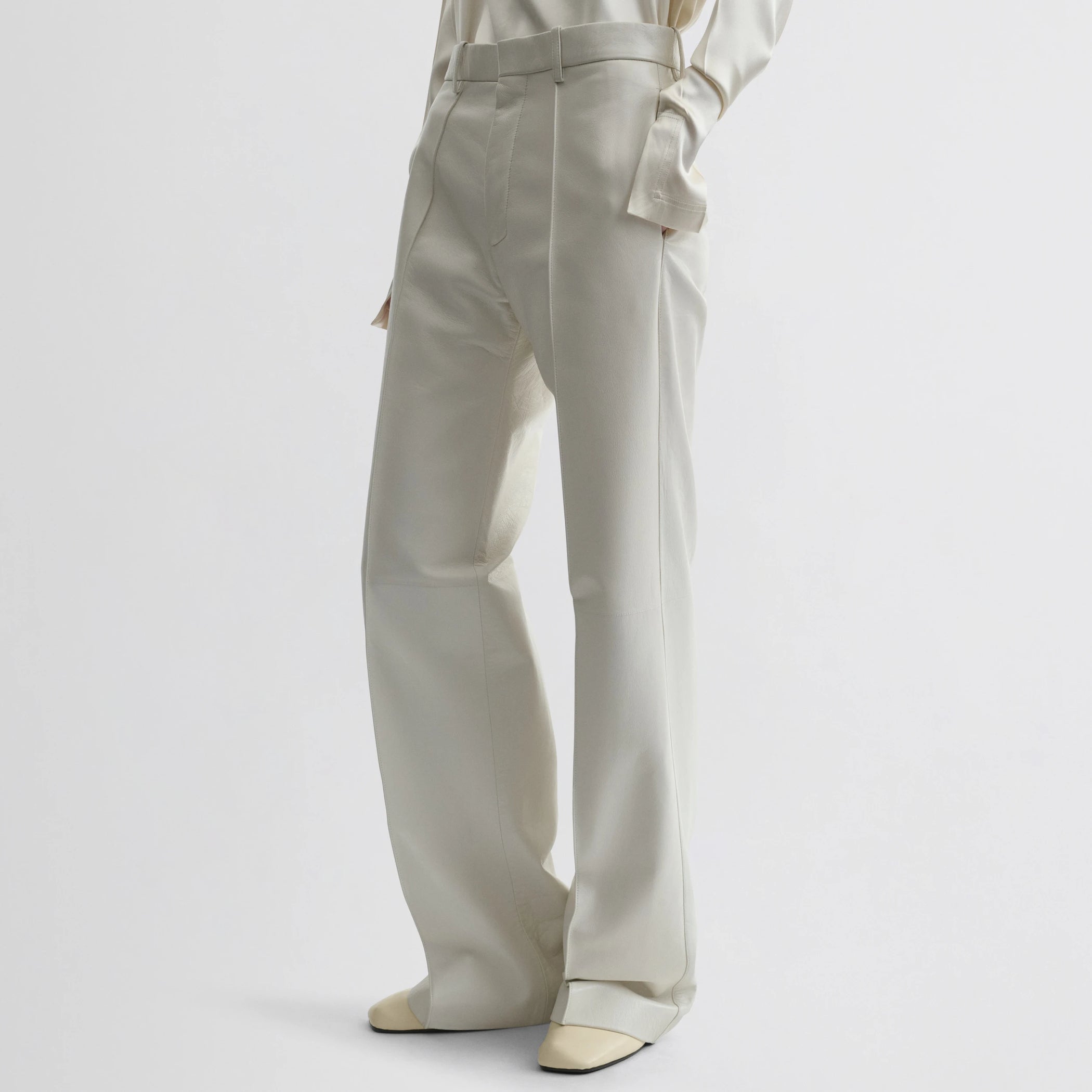 Front view of model wearing boyish trousers in white leather.