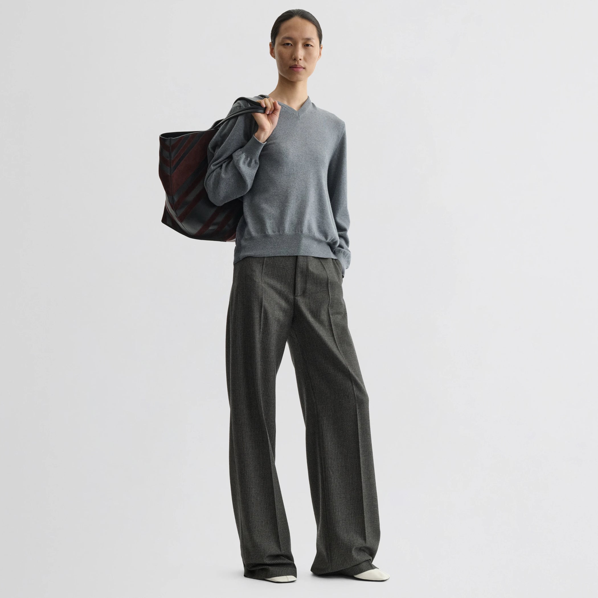 Front view of model wearing backed v-neck sweater in light grey wool.