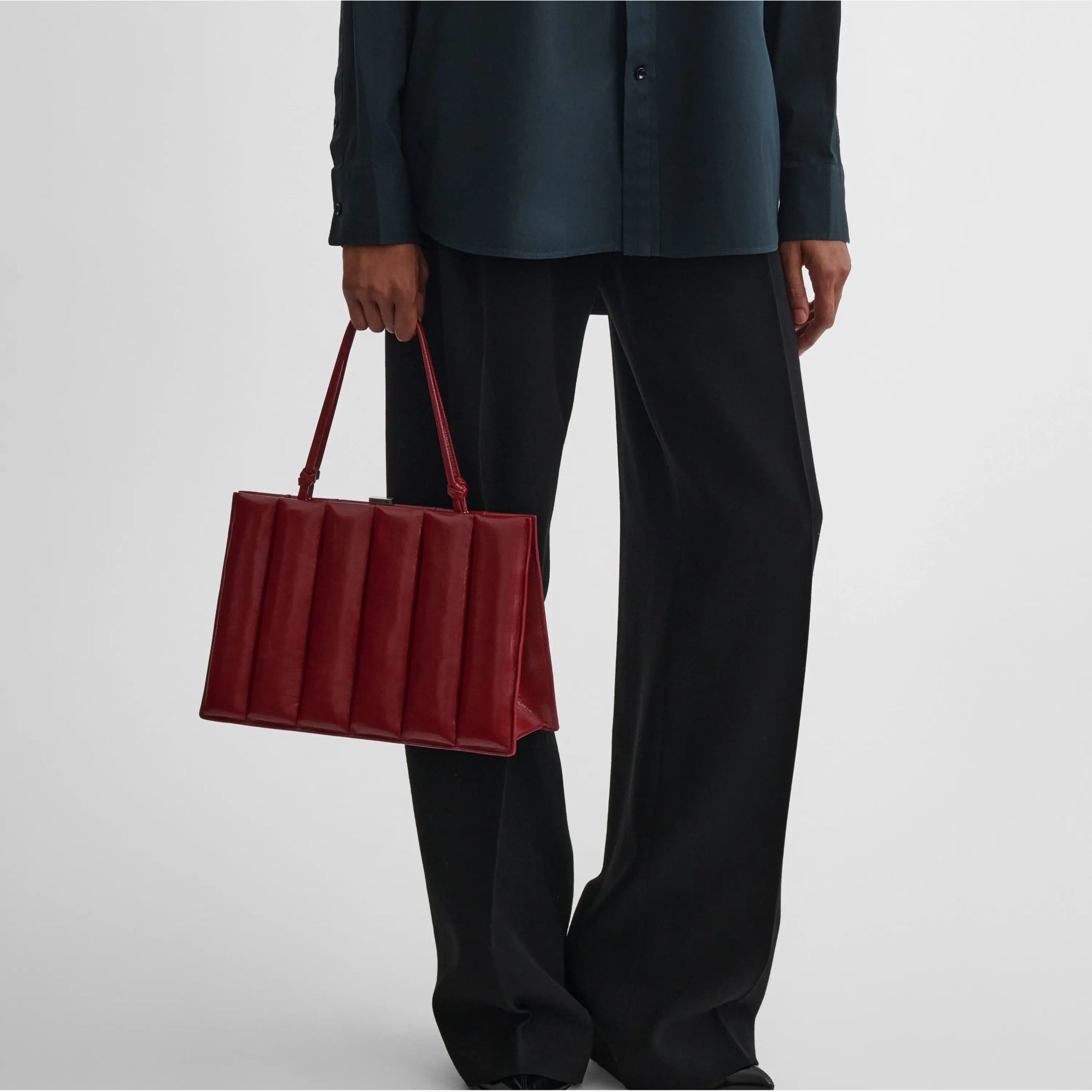 Front view of model holding drive top handle bag medium in shiny calf red 