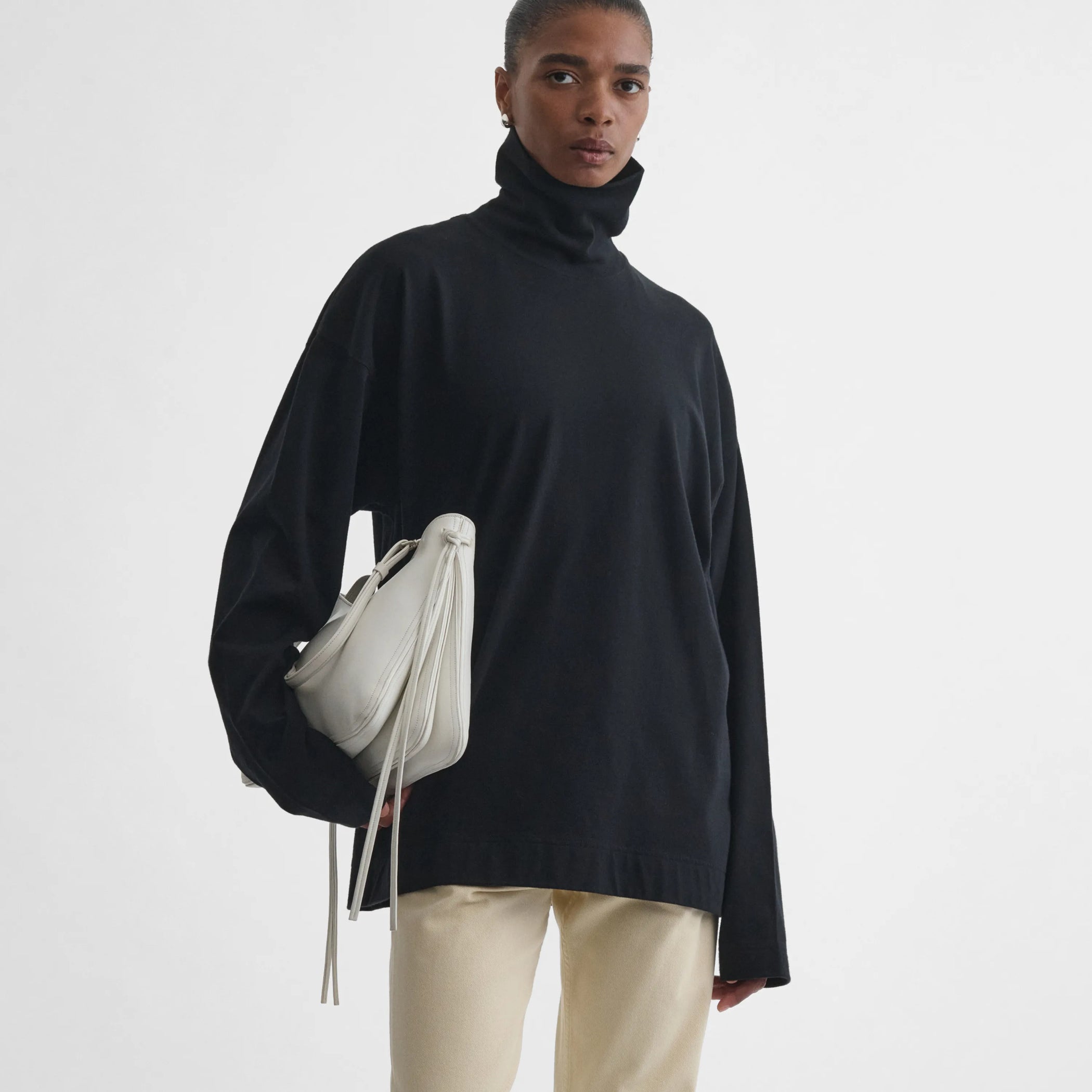 Front view of model holding the Gig bag in white leather 
