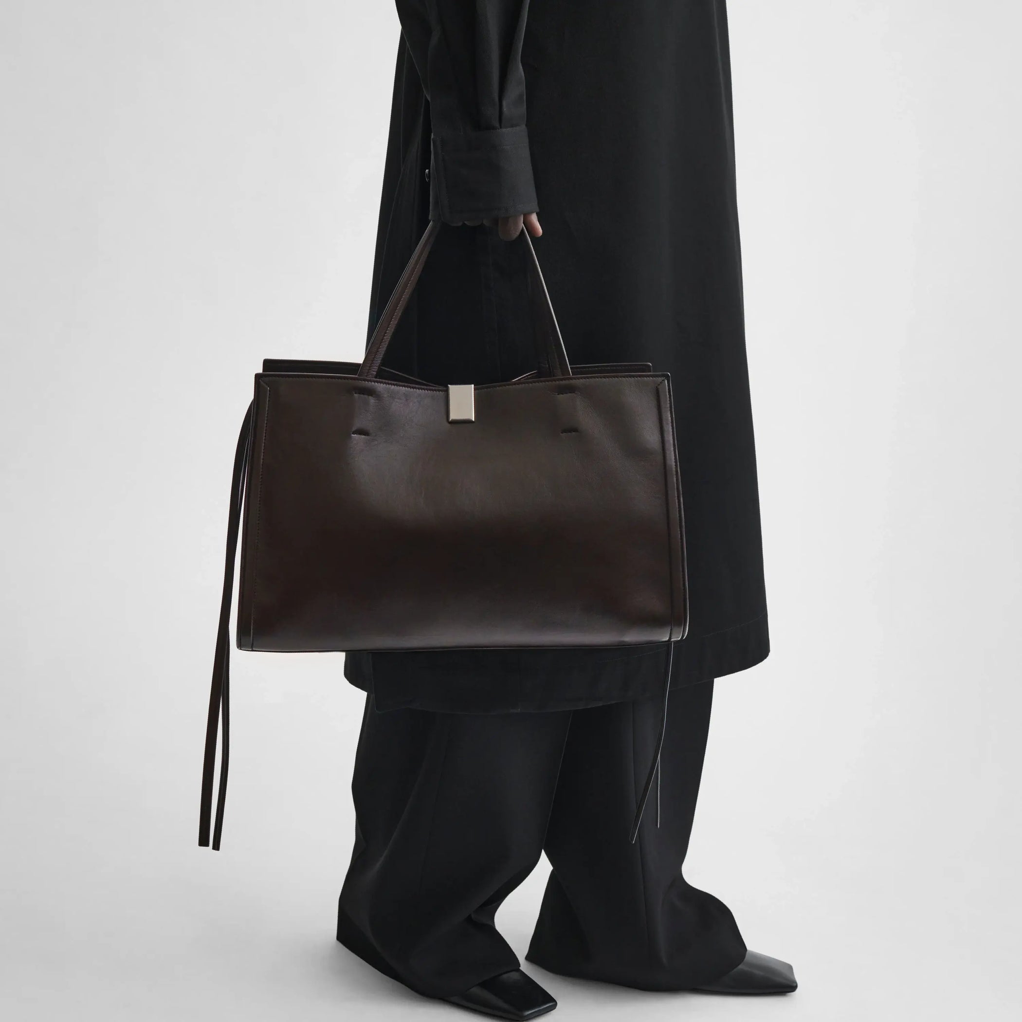 Model holding medium kit cabas in chocolate brown leather. 