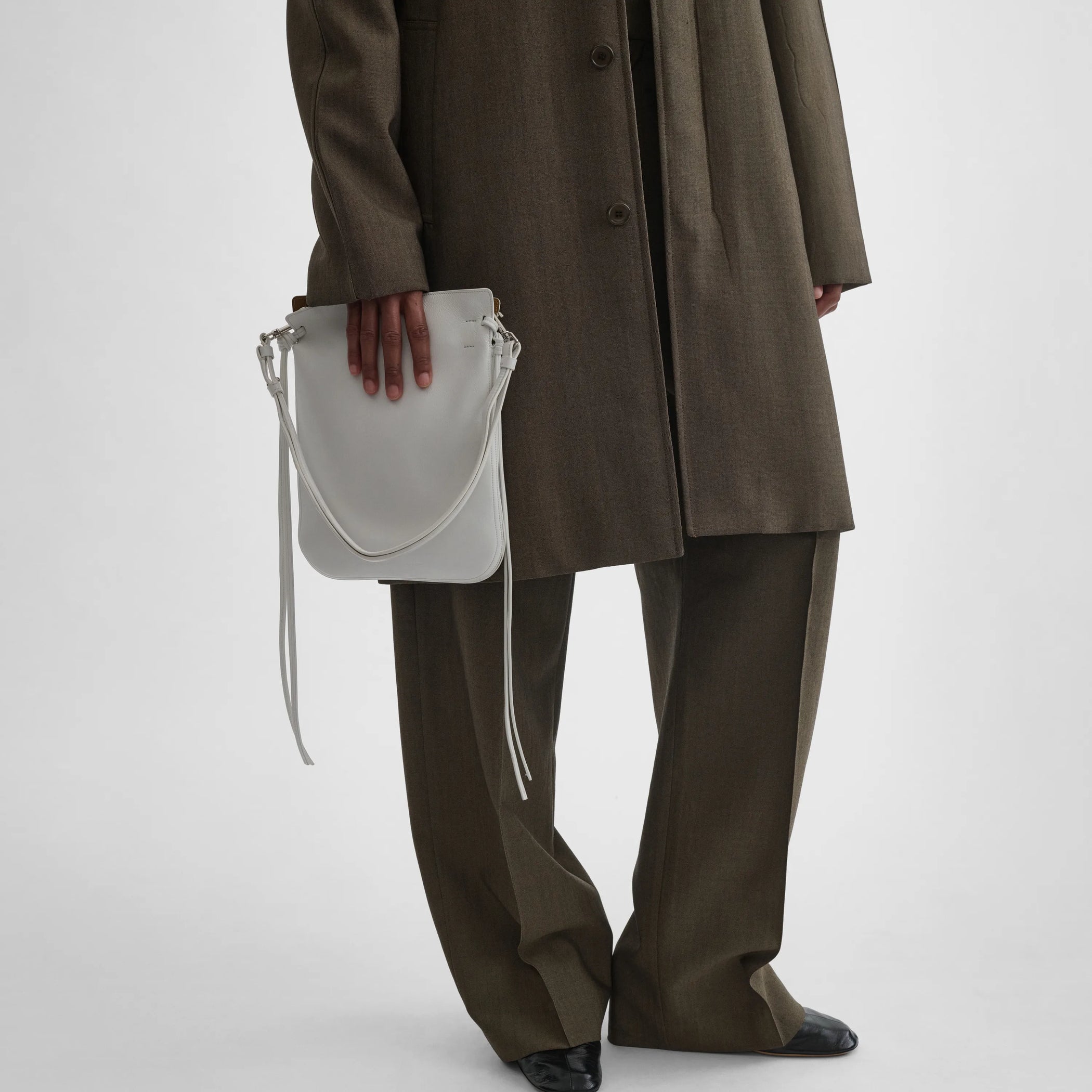 Front view of model holding gig tie pouch in soft calf white 