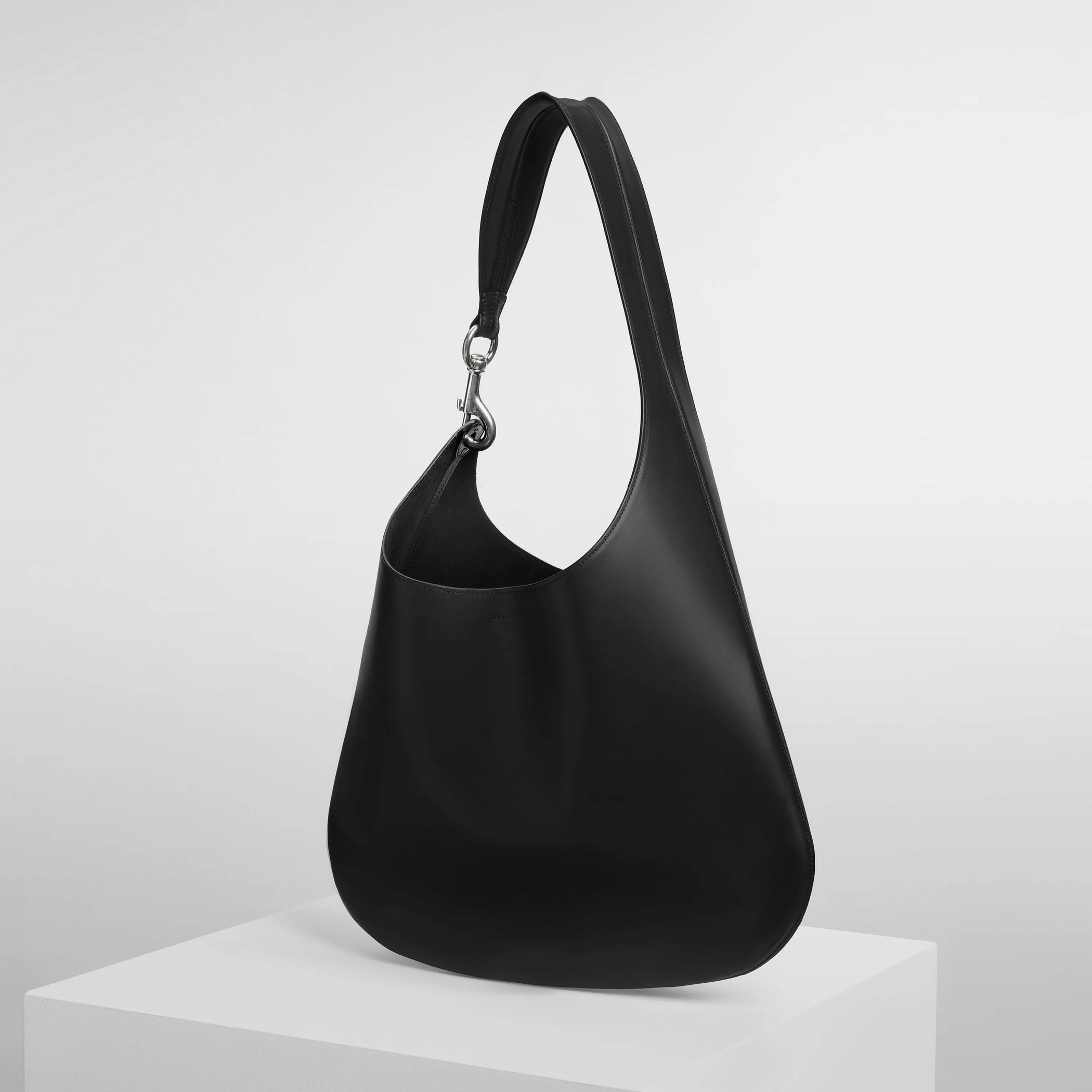 Angled side view of bean sling bag in black leather.
