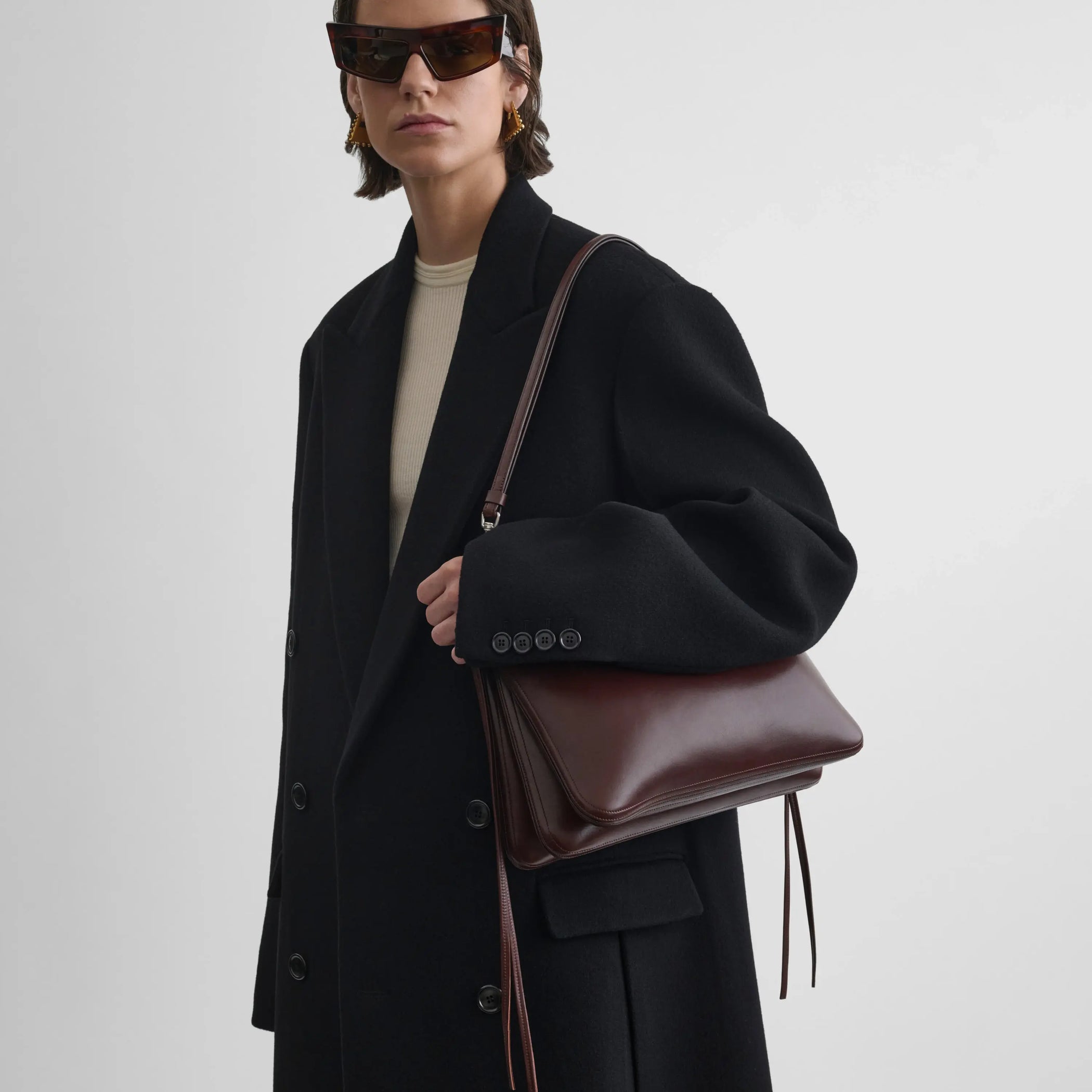 Front view of model wearing the gig shoulder bag in soft calf cognac 