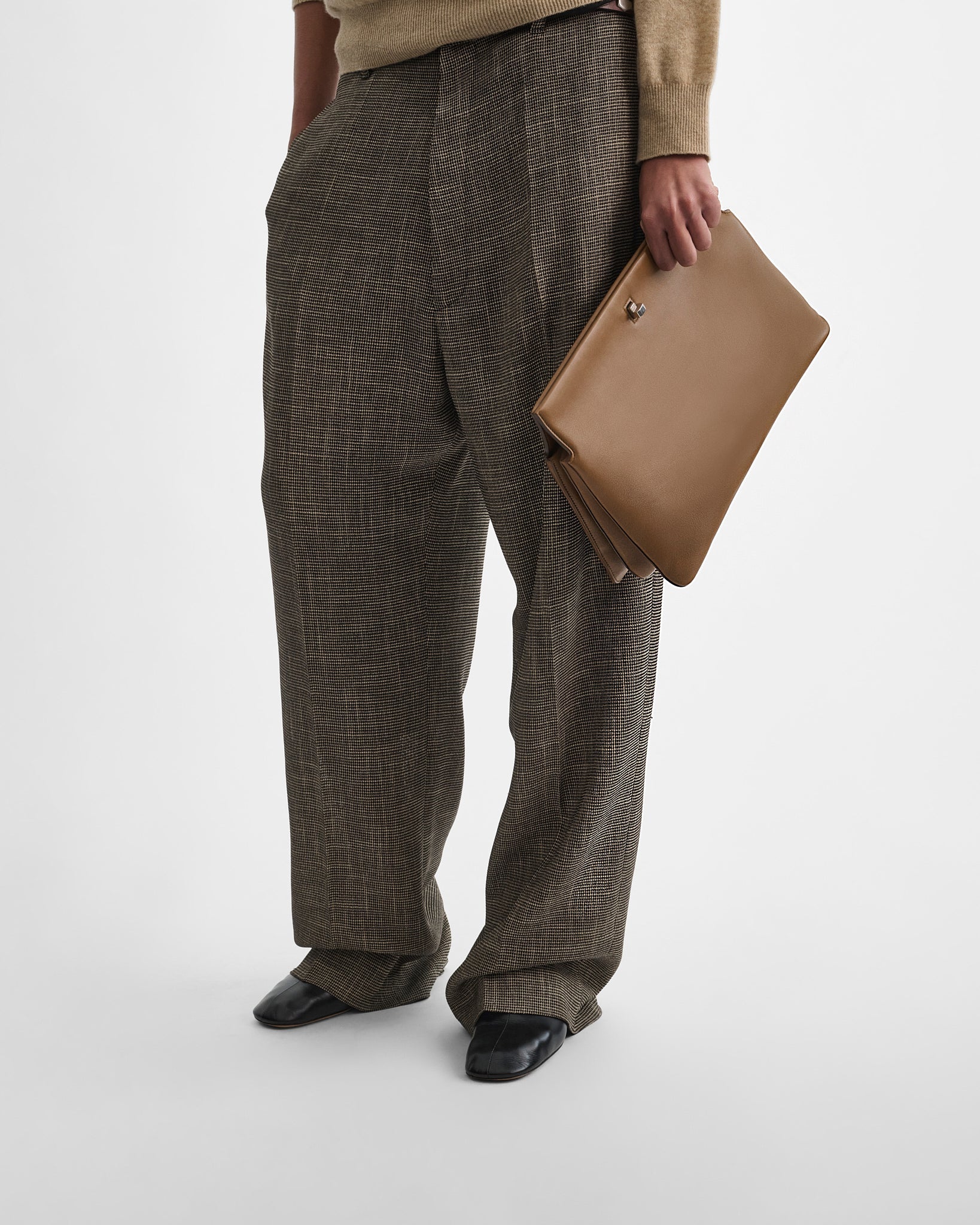 Front view of model holding the TRIPLEX CLUTCH in caramel leather.