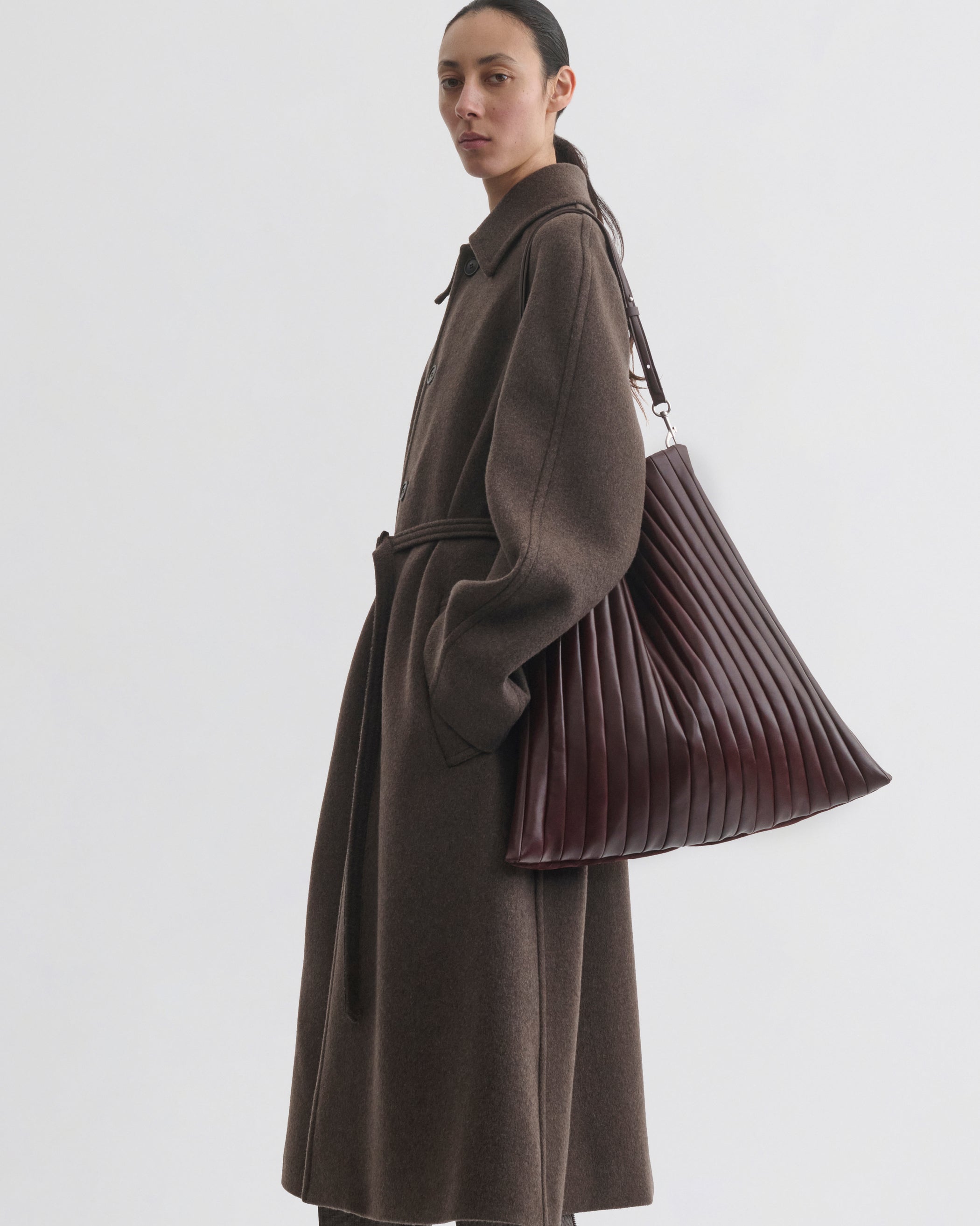 Side view of model wearing ACCORDION BAG in oxblood leather