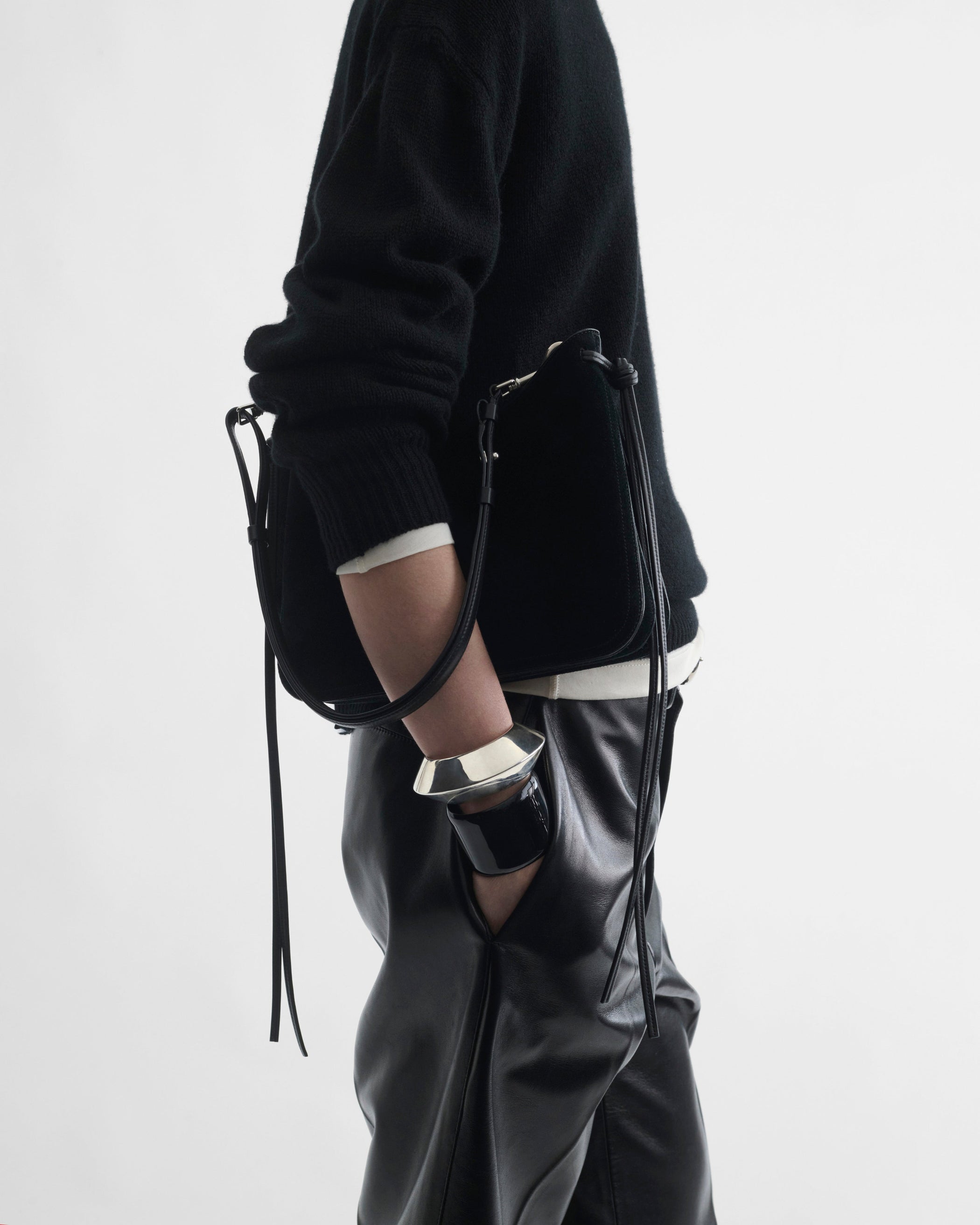 Side view of model holding SMALL GIG BAG in black suede