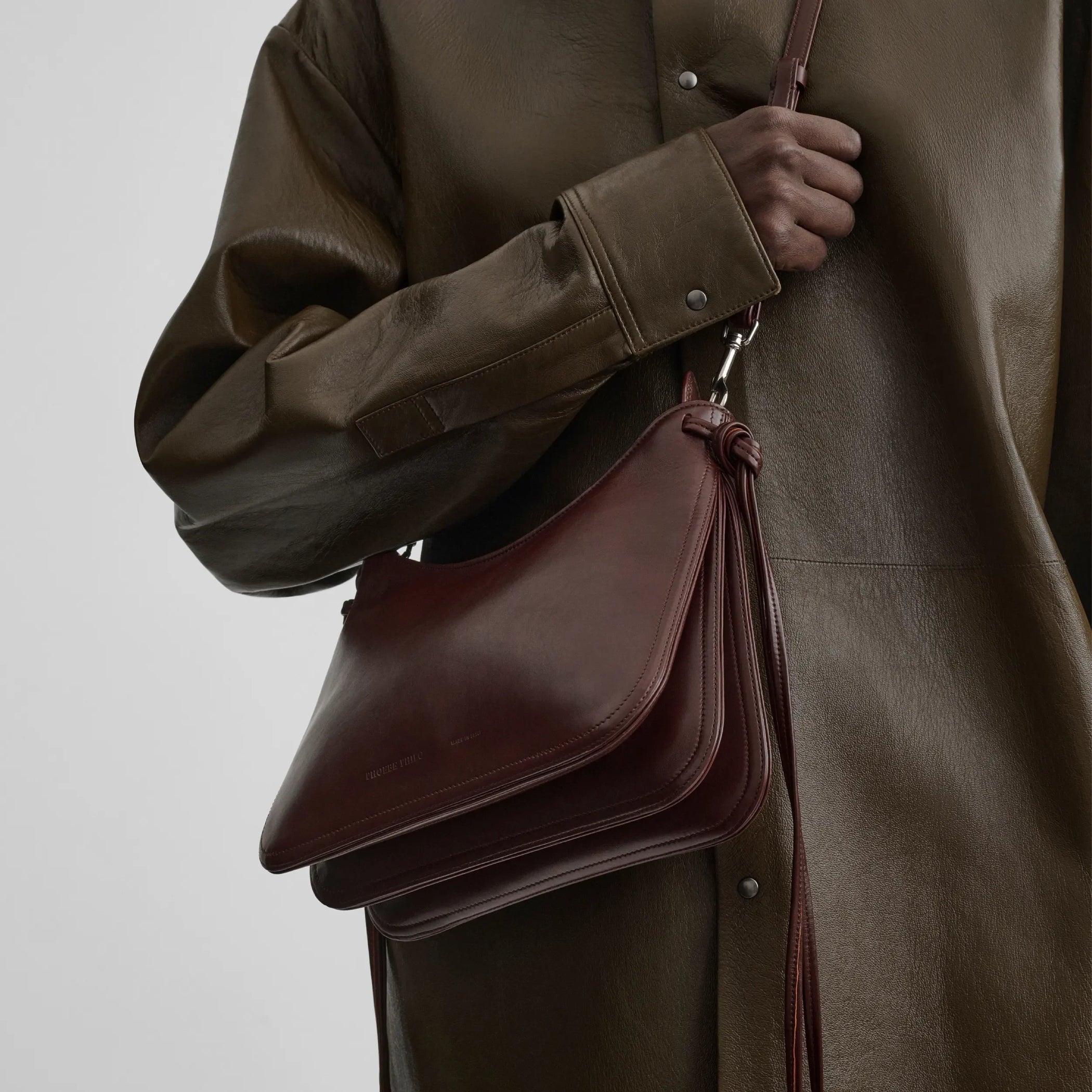 Front view of model holding small gig in cognac leather.