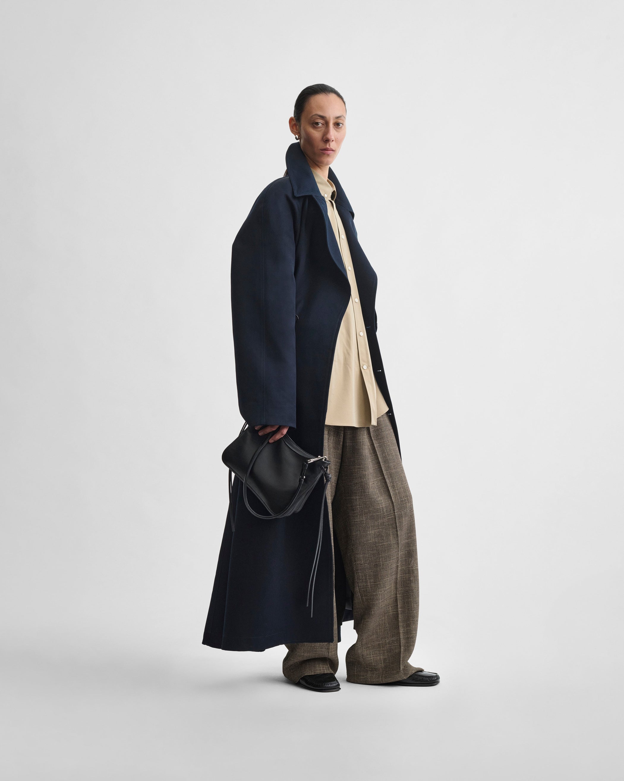 Side view of model holding SMALL GIG BAG in black leather