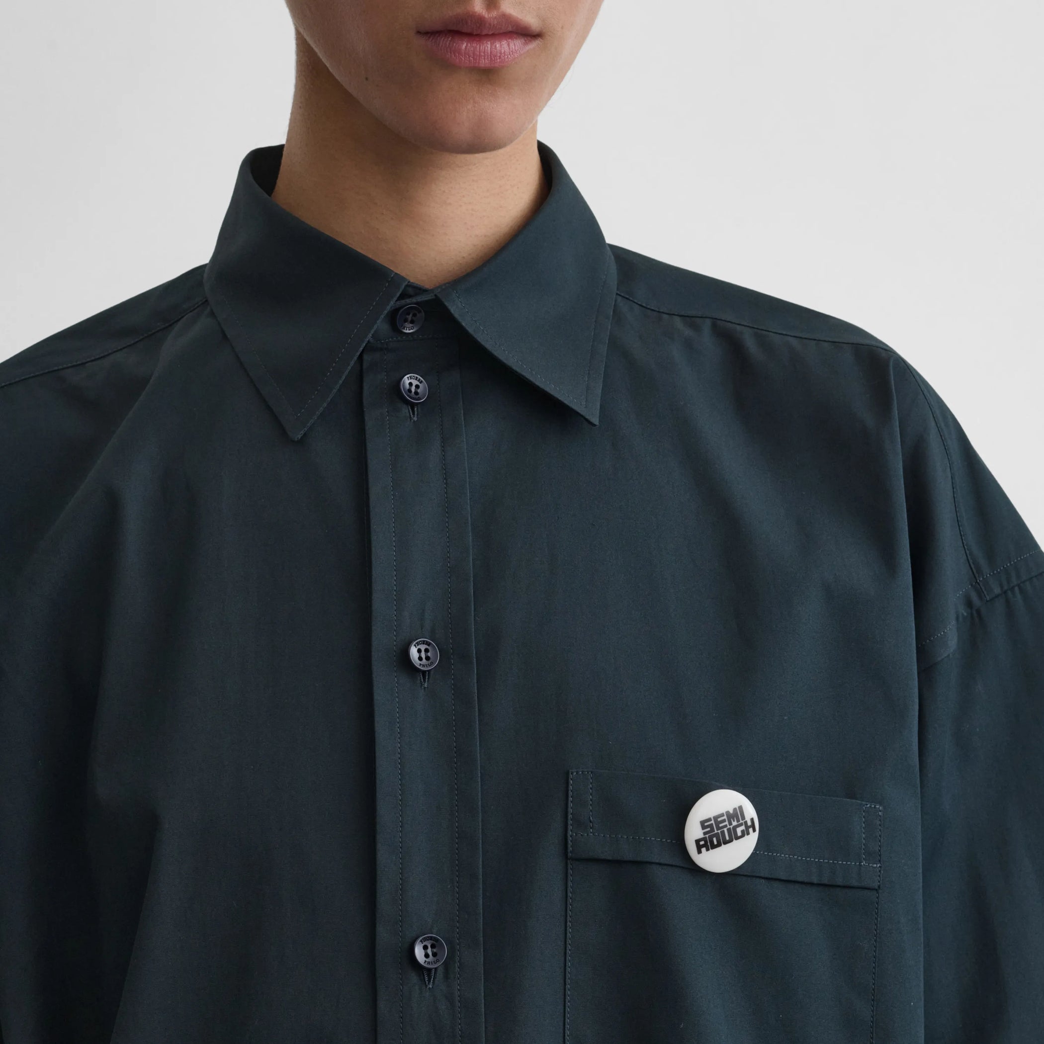 Front view of model wearing the semi rough badge in black/white 
