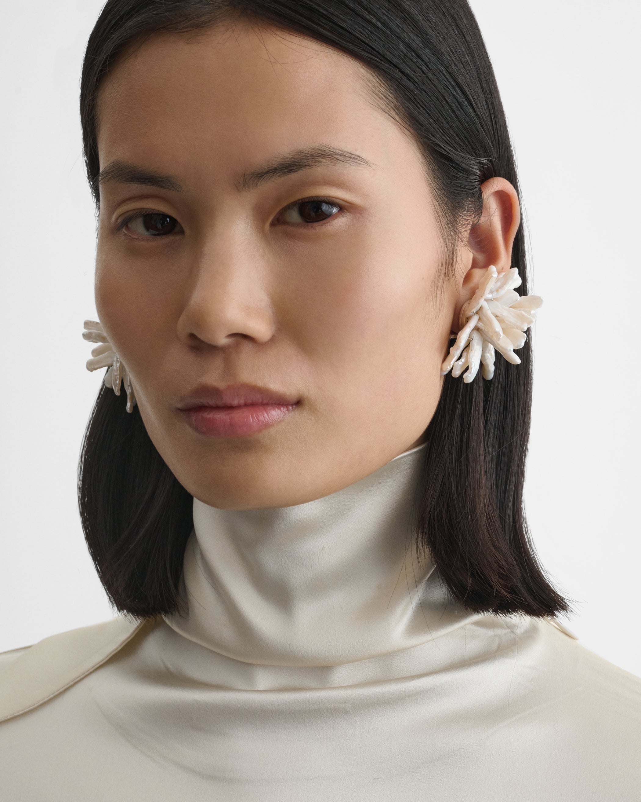 Front view of model wearing CLUSTER EARRINGS in silver cream resin