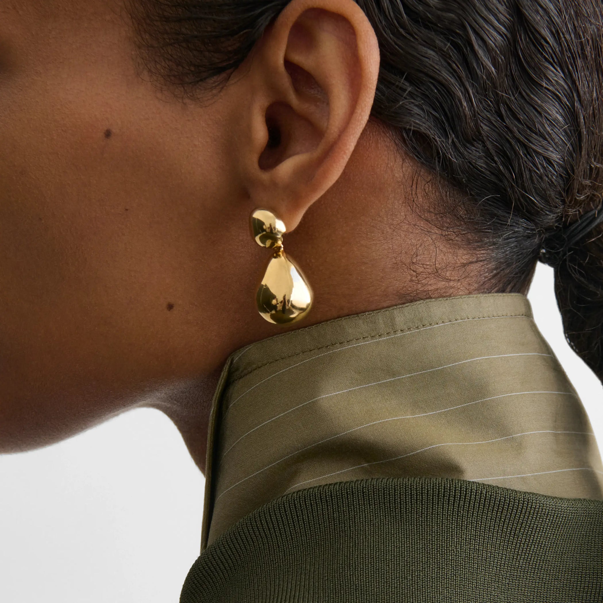 Model wearing double ball earrings in gold. 