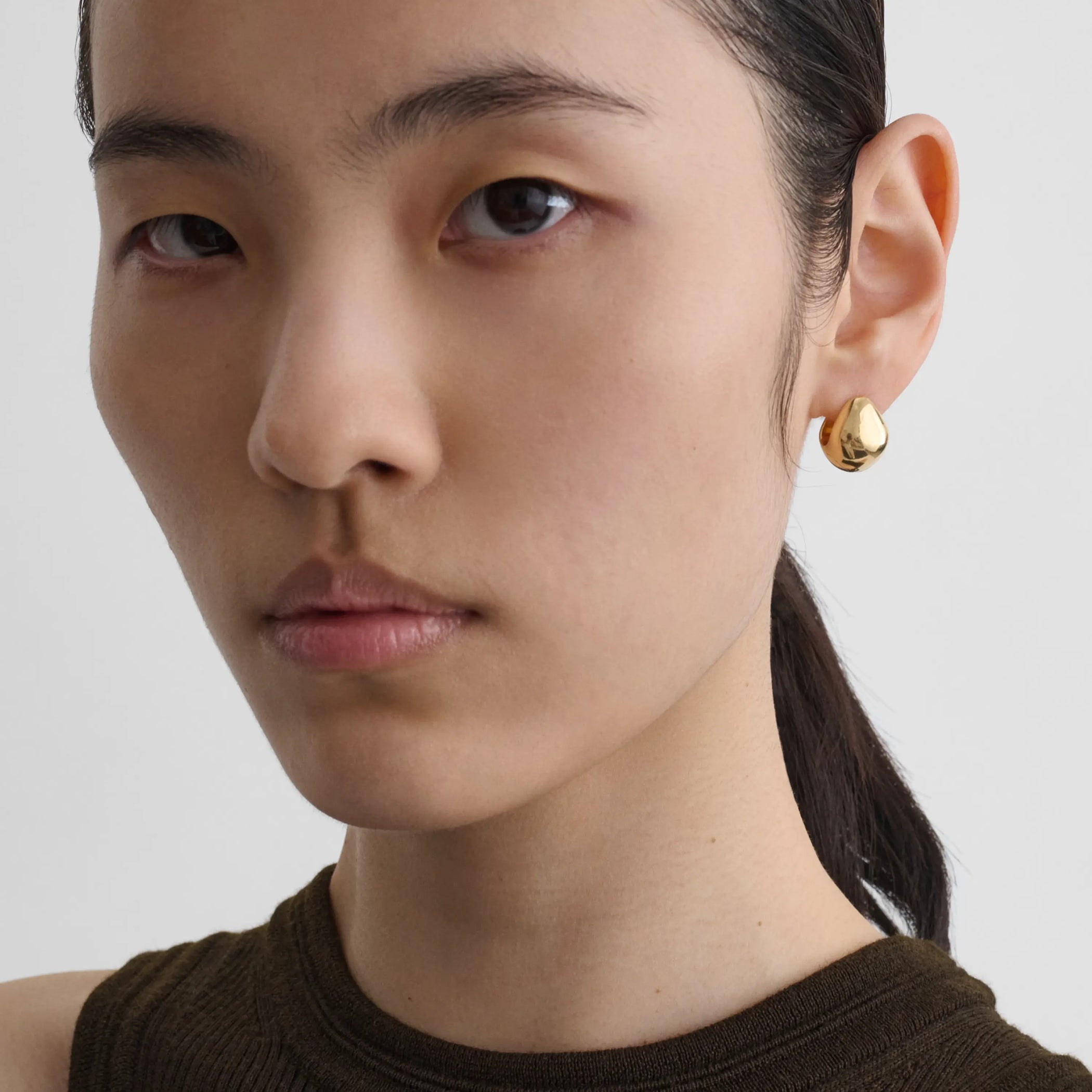 Model wearing pebble stud earrings in plated sliver 