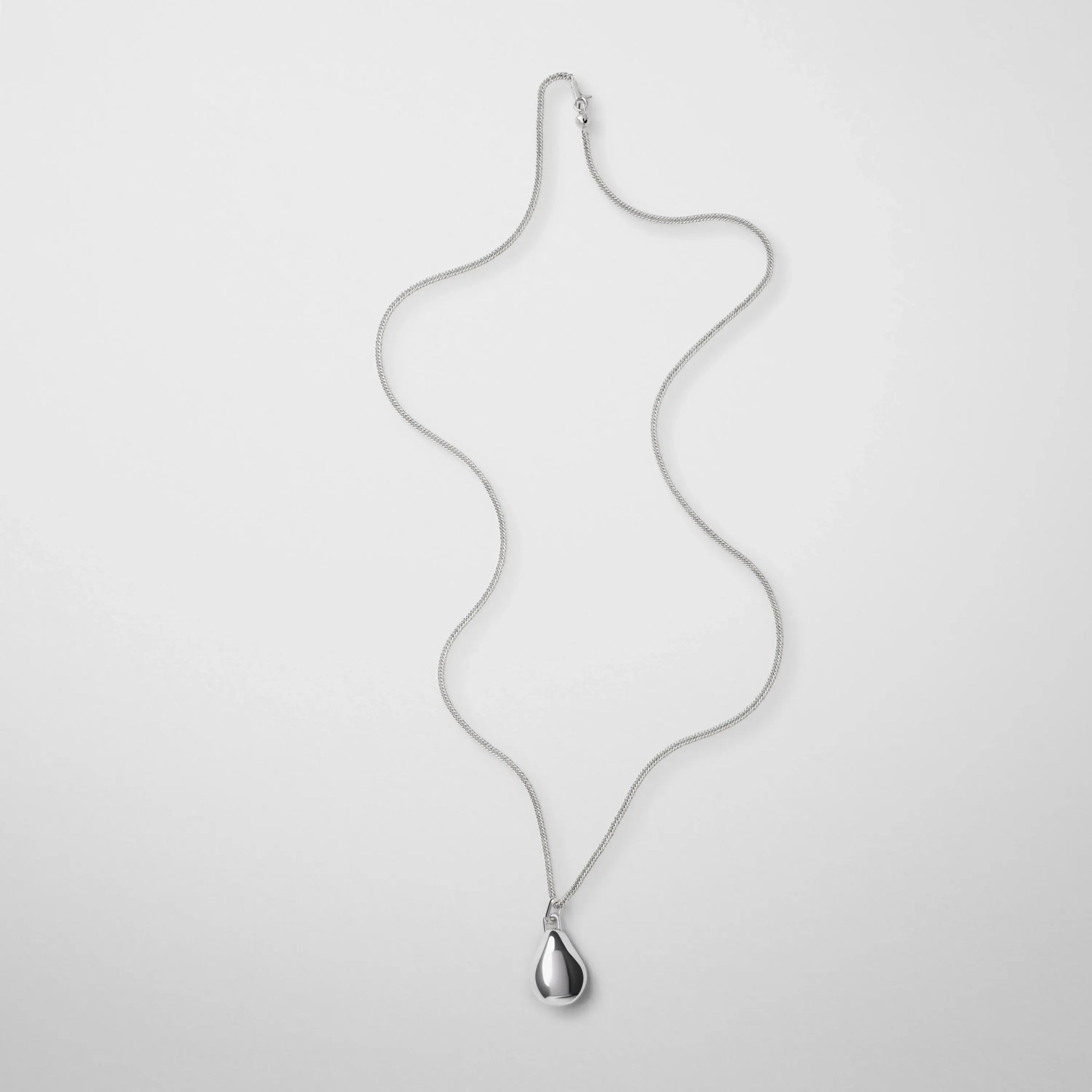 Flat lay view of small pebble pendant in sliver