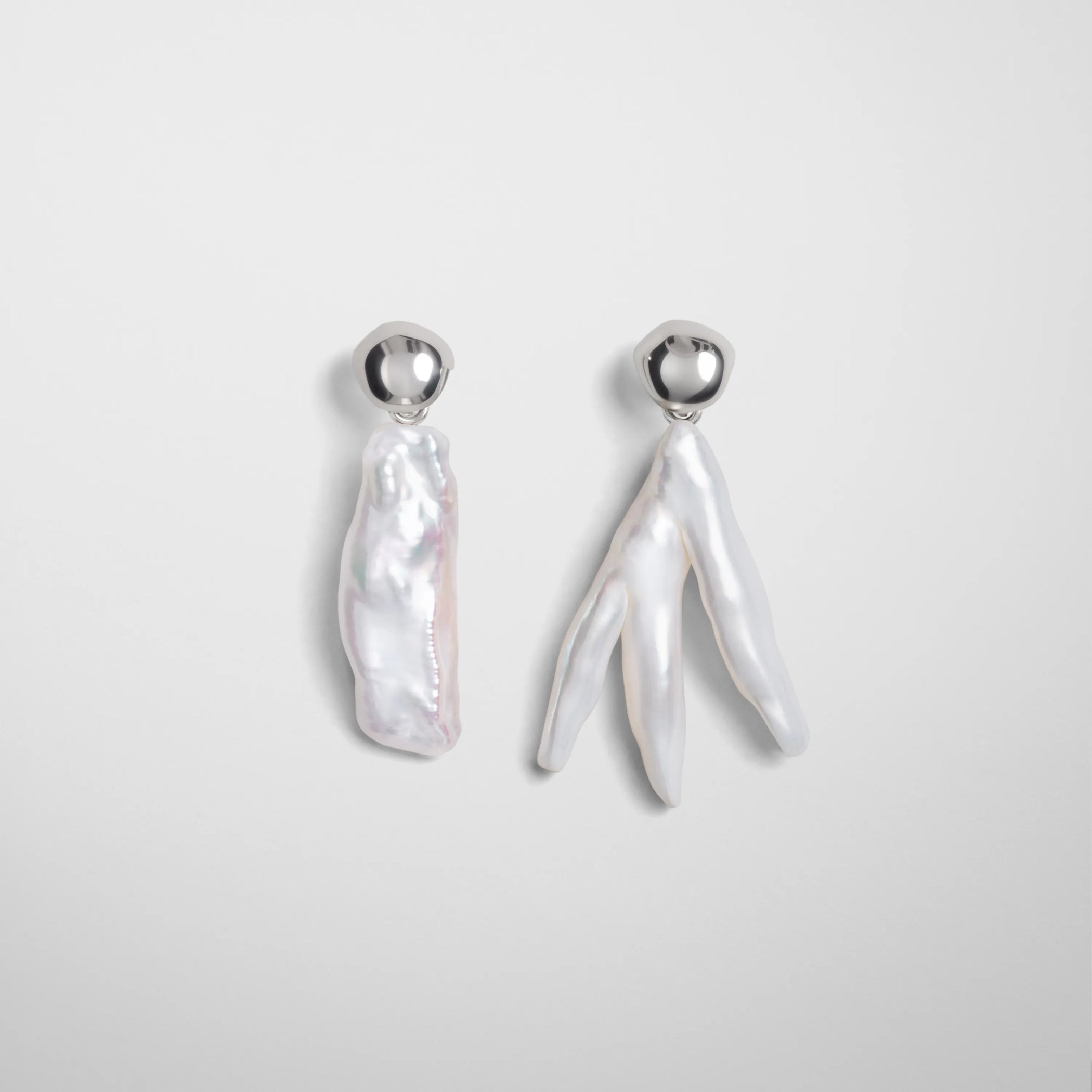 Front view of asymmetric pearl earrings in silver