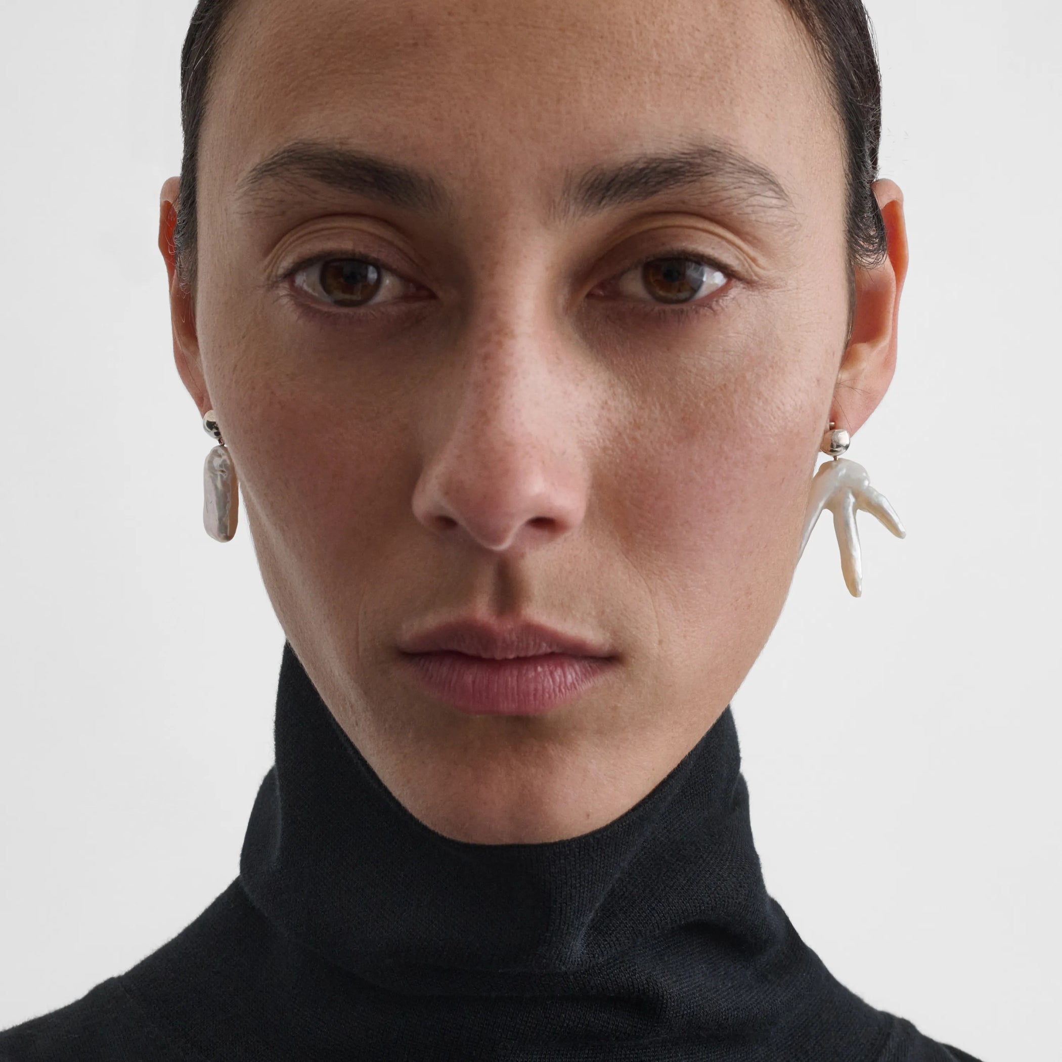 Front view of model wearing the asymmetric pearl earrings in silver 
