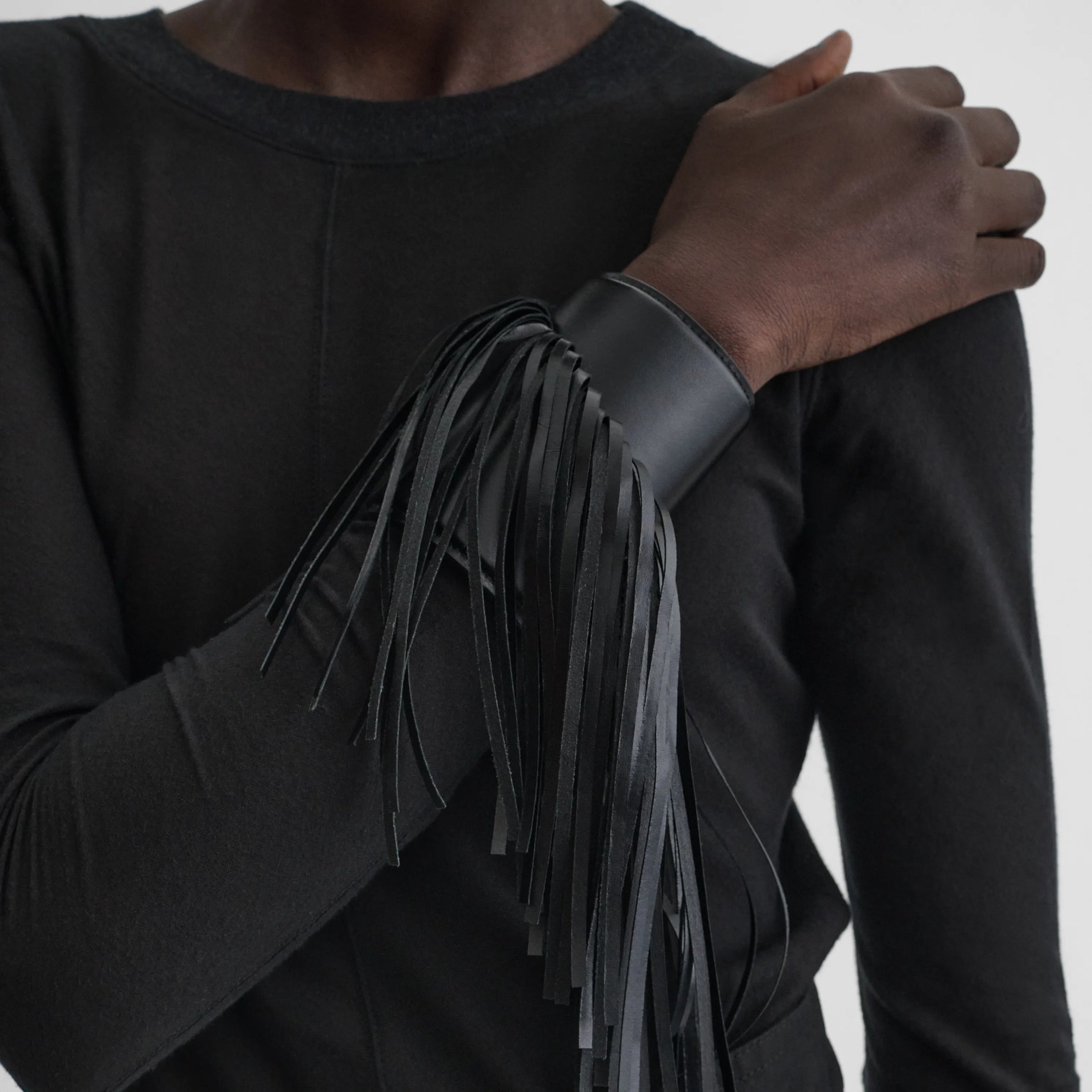 Front view of model wearing the fringe cuff in black 