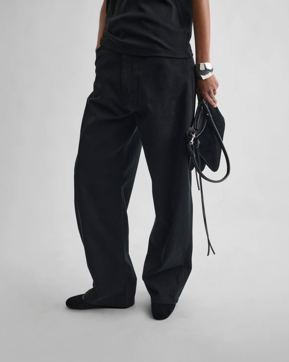 Front detail view of model wearing DROP JEANS in black cotton