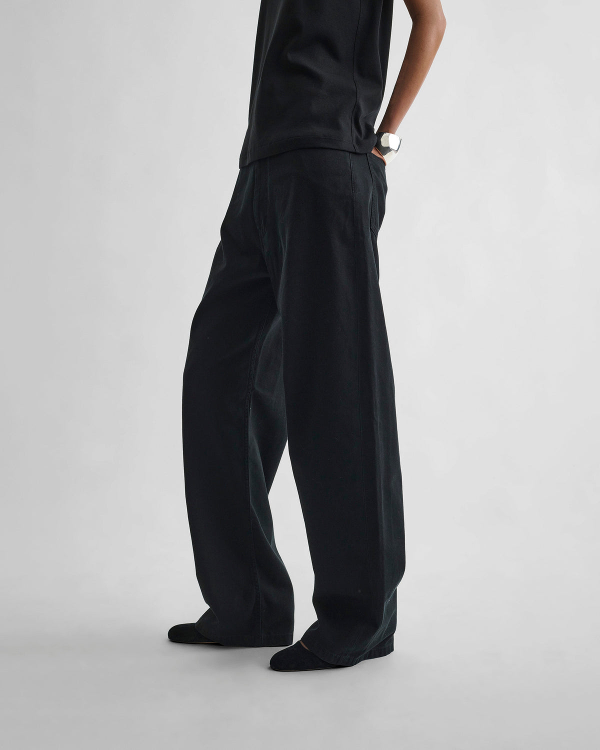 Side view of model wearing DROP JEANS in black cotton