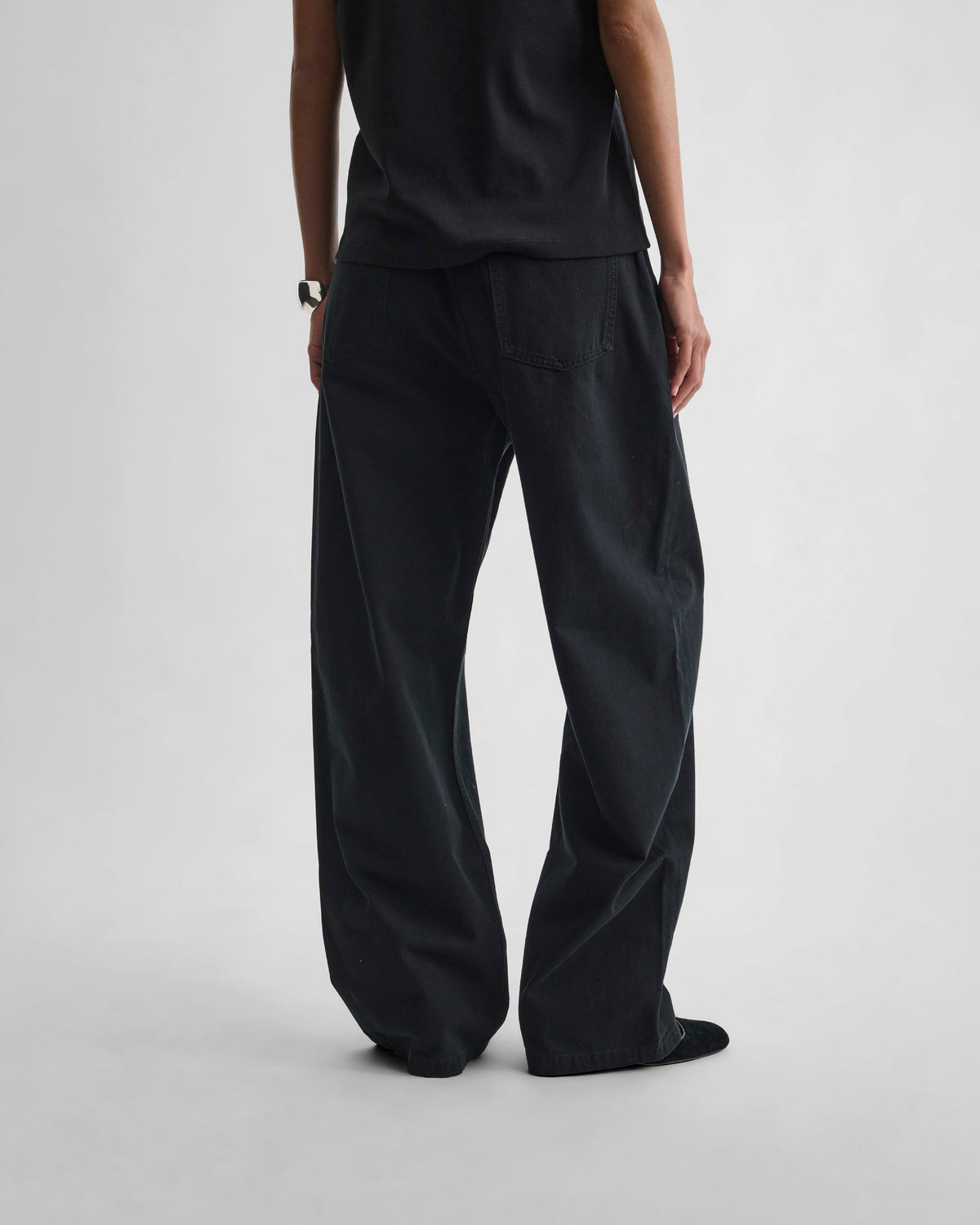 Back view of model wearing DROP JEANS in black cotton