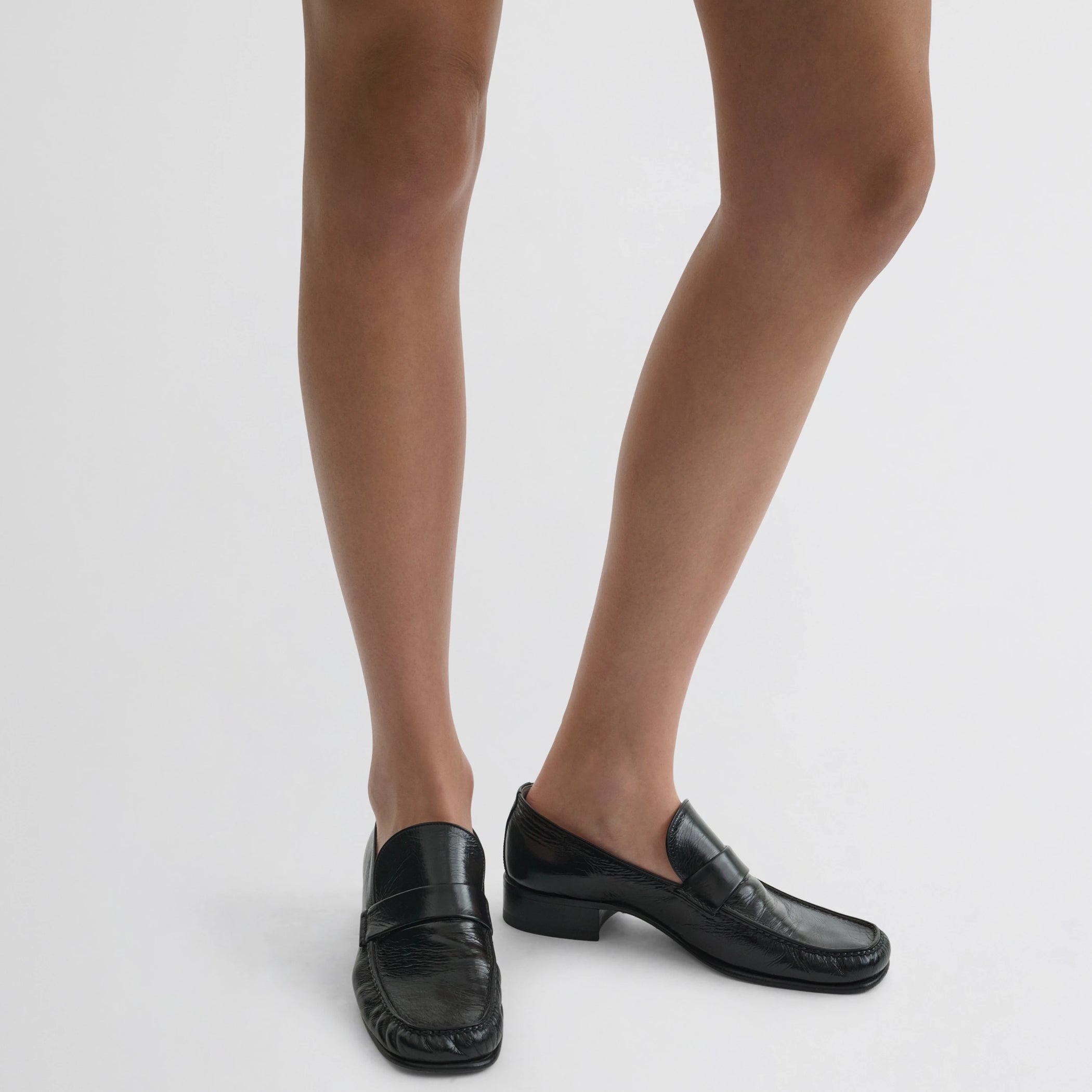Front view of model wearing man’s loafer in black leather.