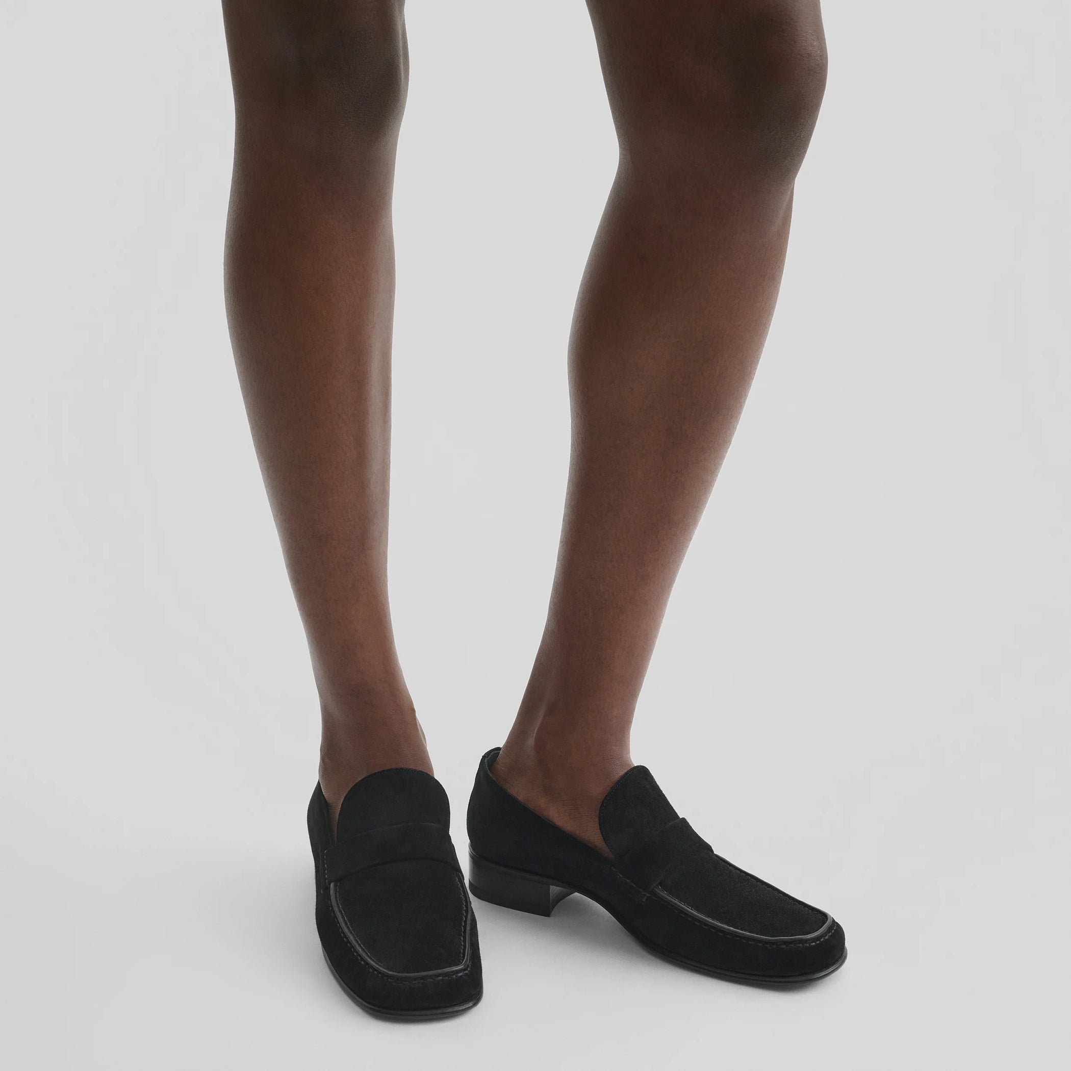 Model wearing man&#39;s loafer in black suede leather.