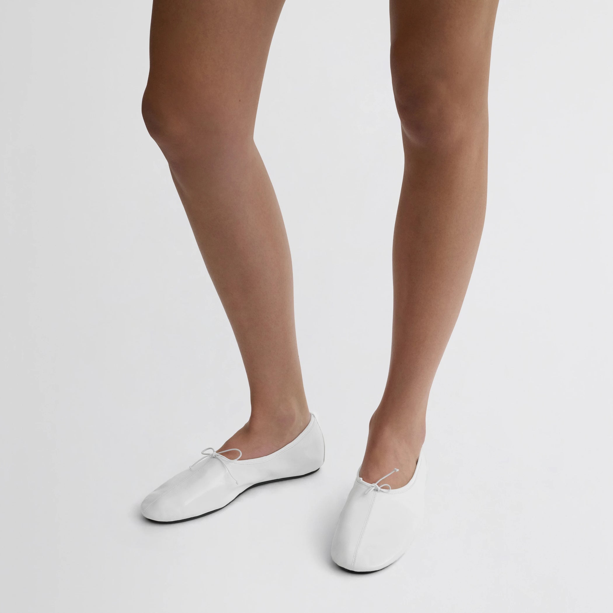Front view of model wearing gathered flat in white leather.