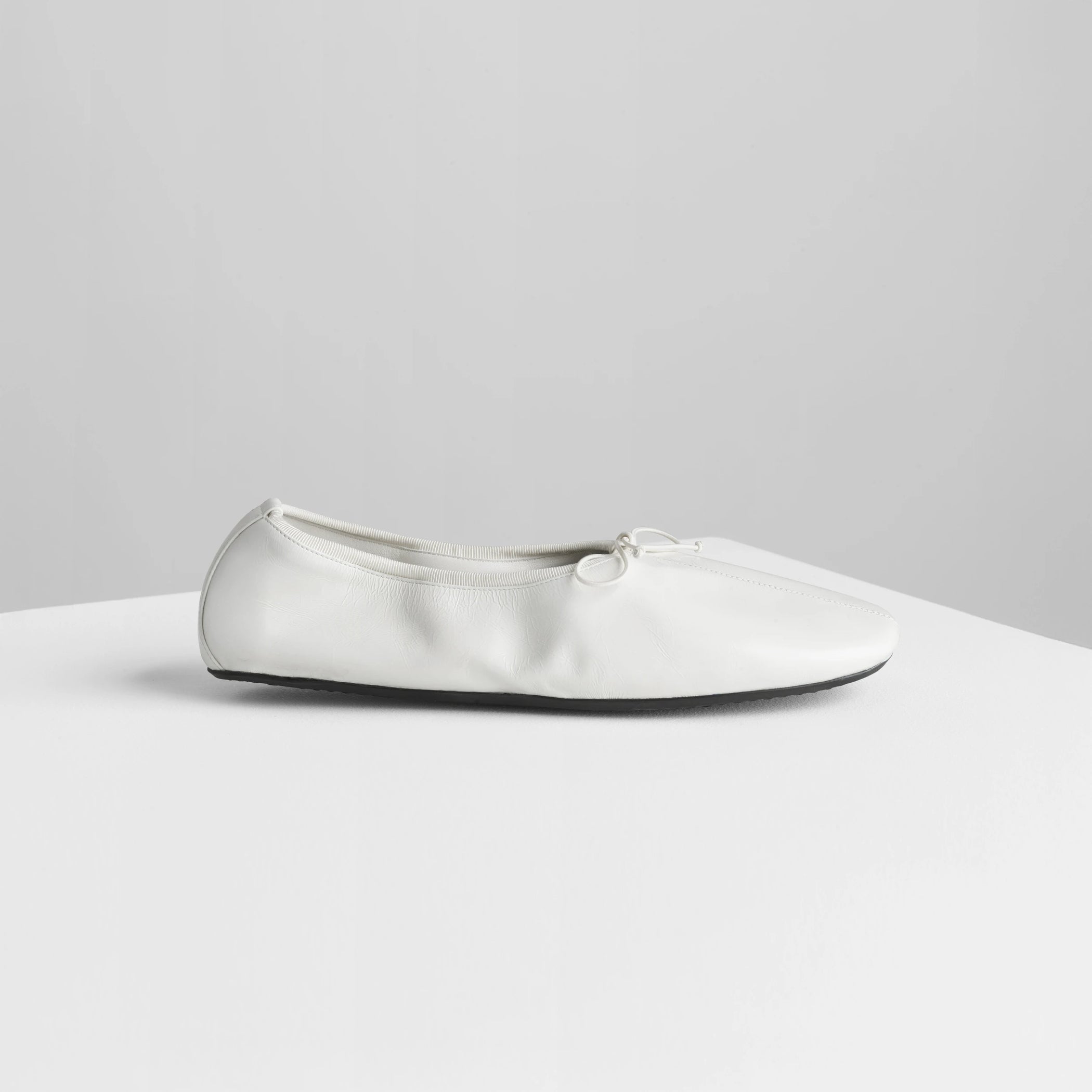 Side view of gathered flat in white leather.