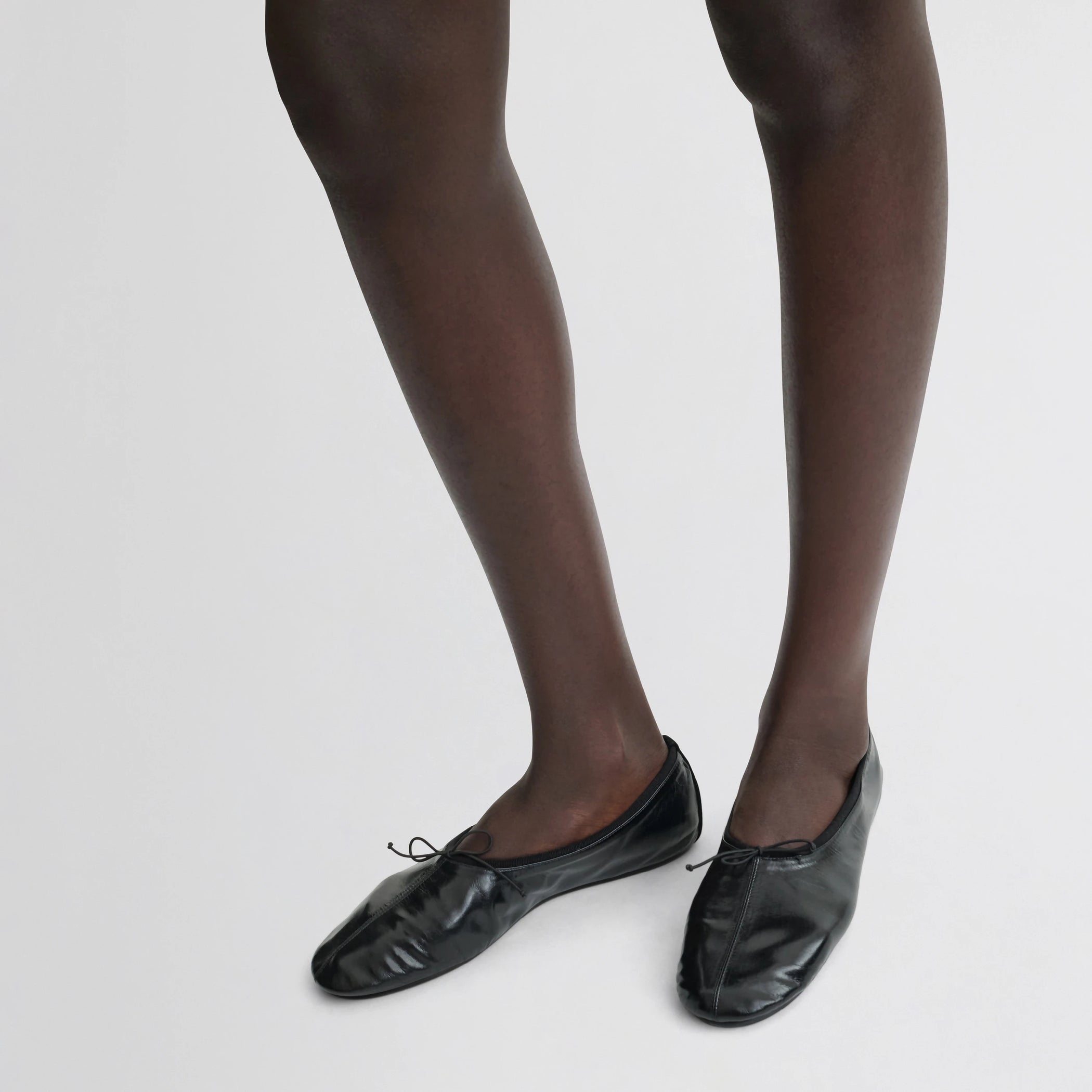 Front view of model wearing gathered flat in black leather.