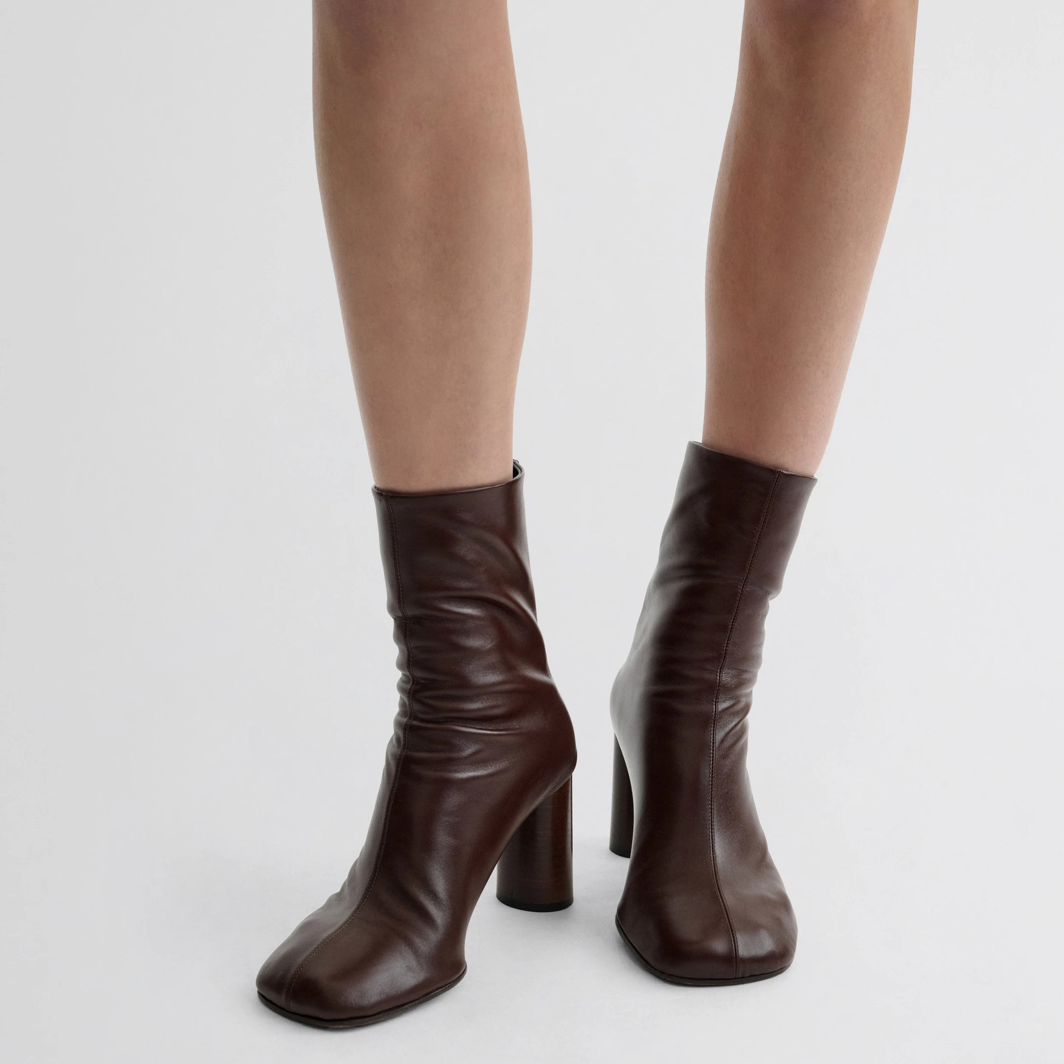 Front view of model wearing tug ankle boot in plum brown leather.
