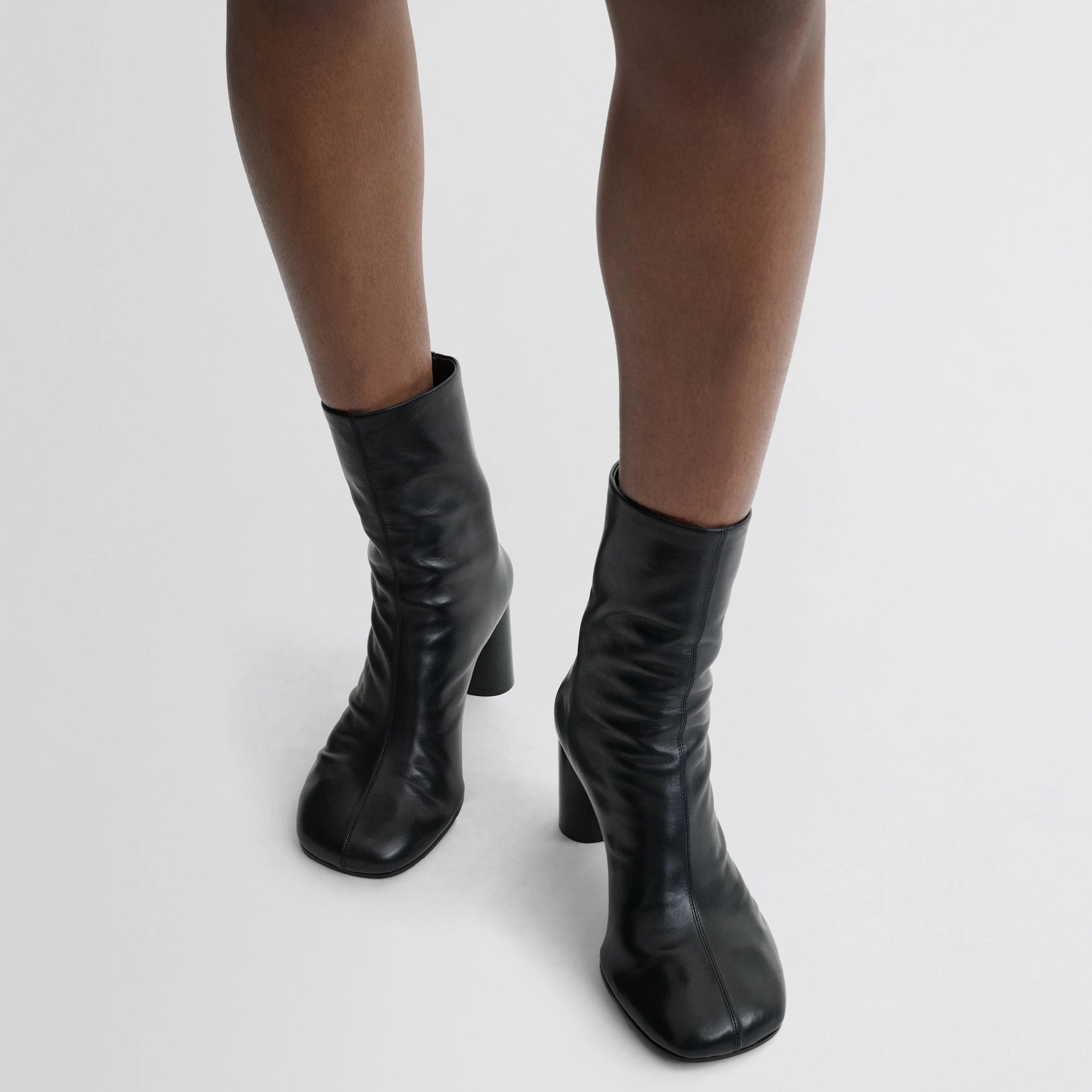 Front view of model wearing tug ankle boot in black leather.