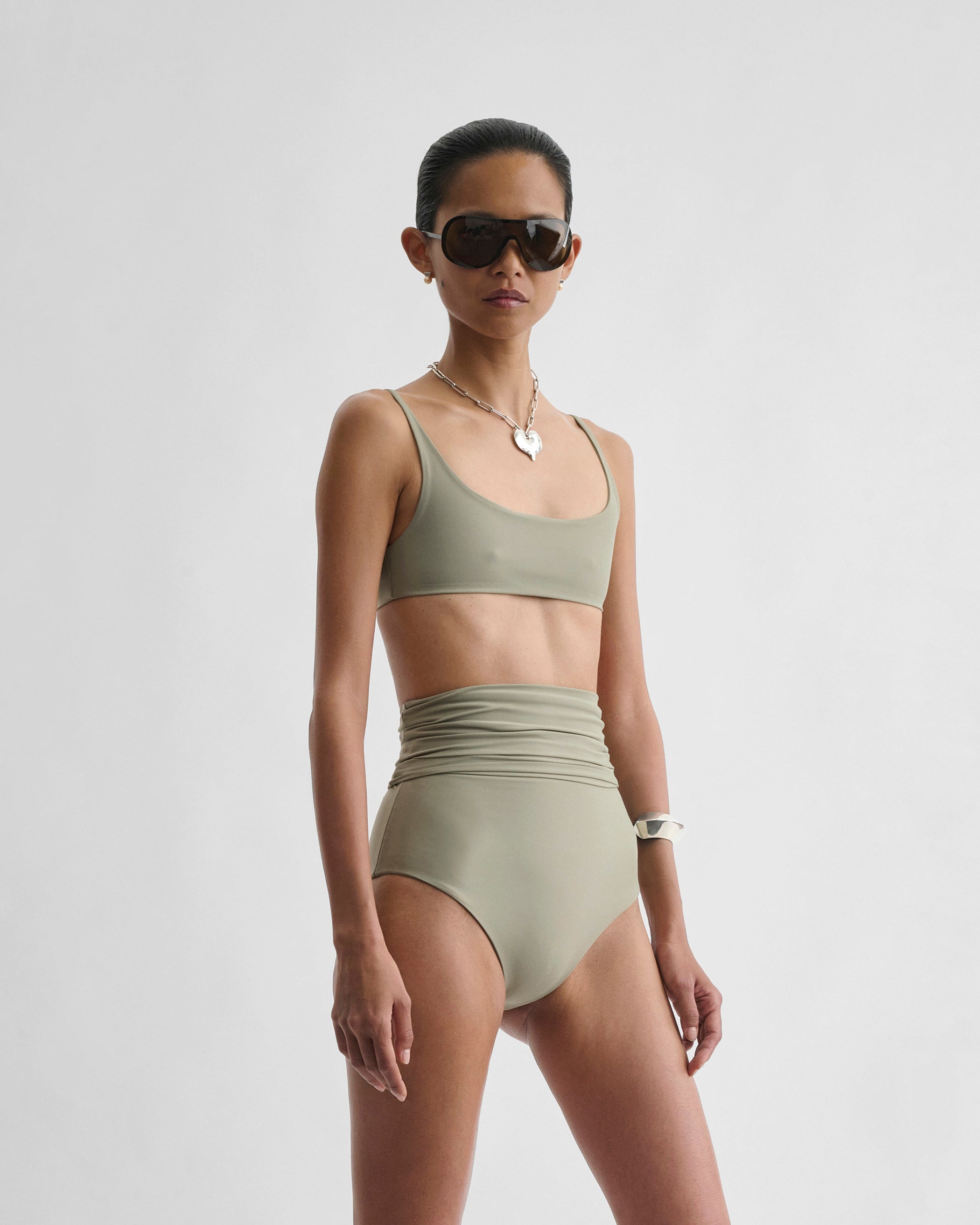 Angled front view of model wearing SCOOP BIKINI TOP in light sage polyamide