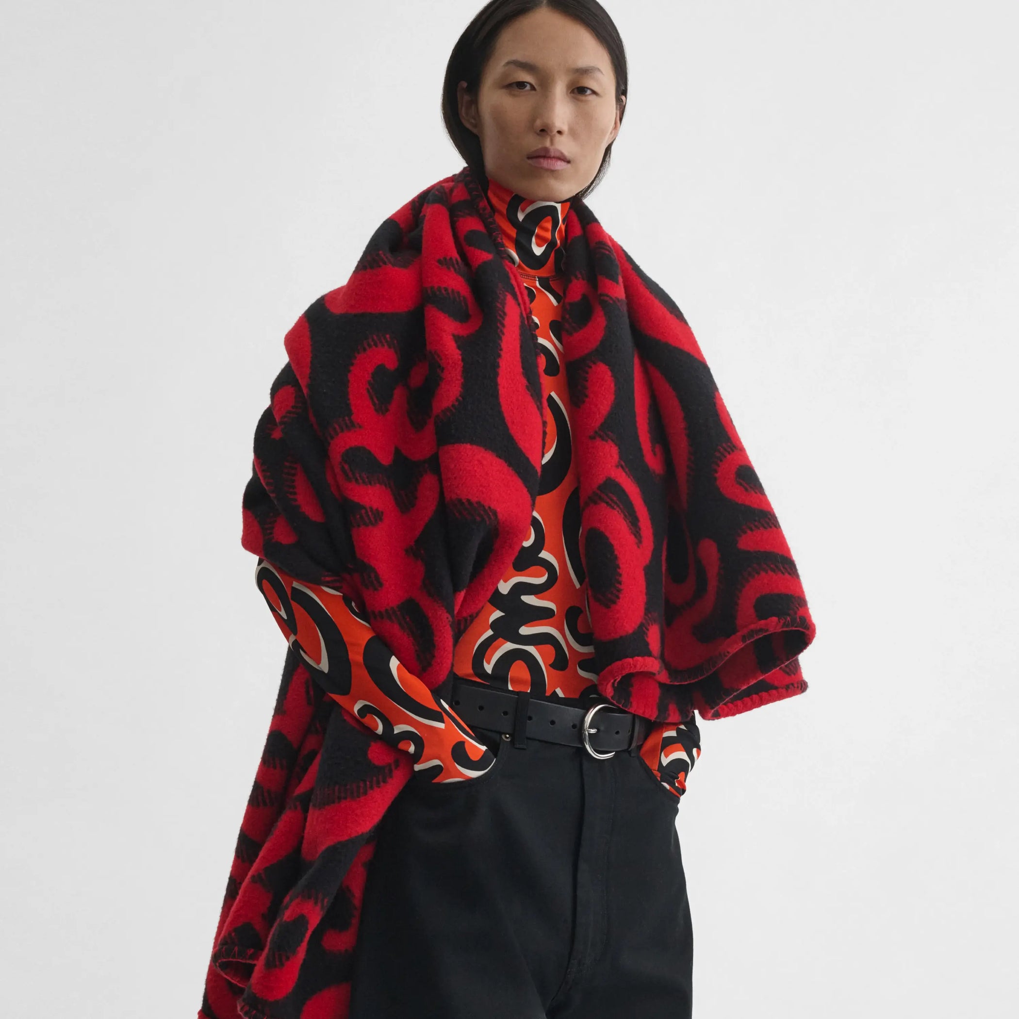 Front view of model wearing Doodle Blanket in red/black. 