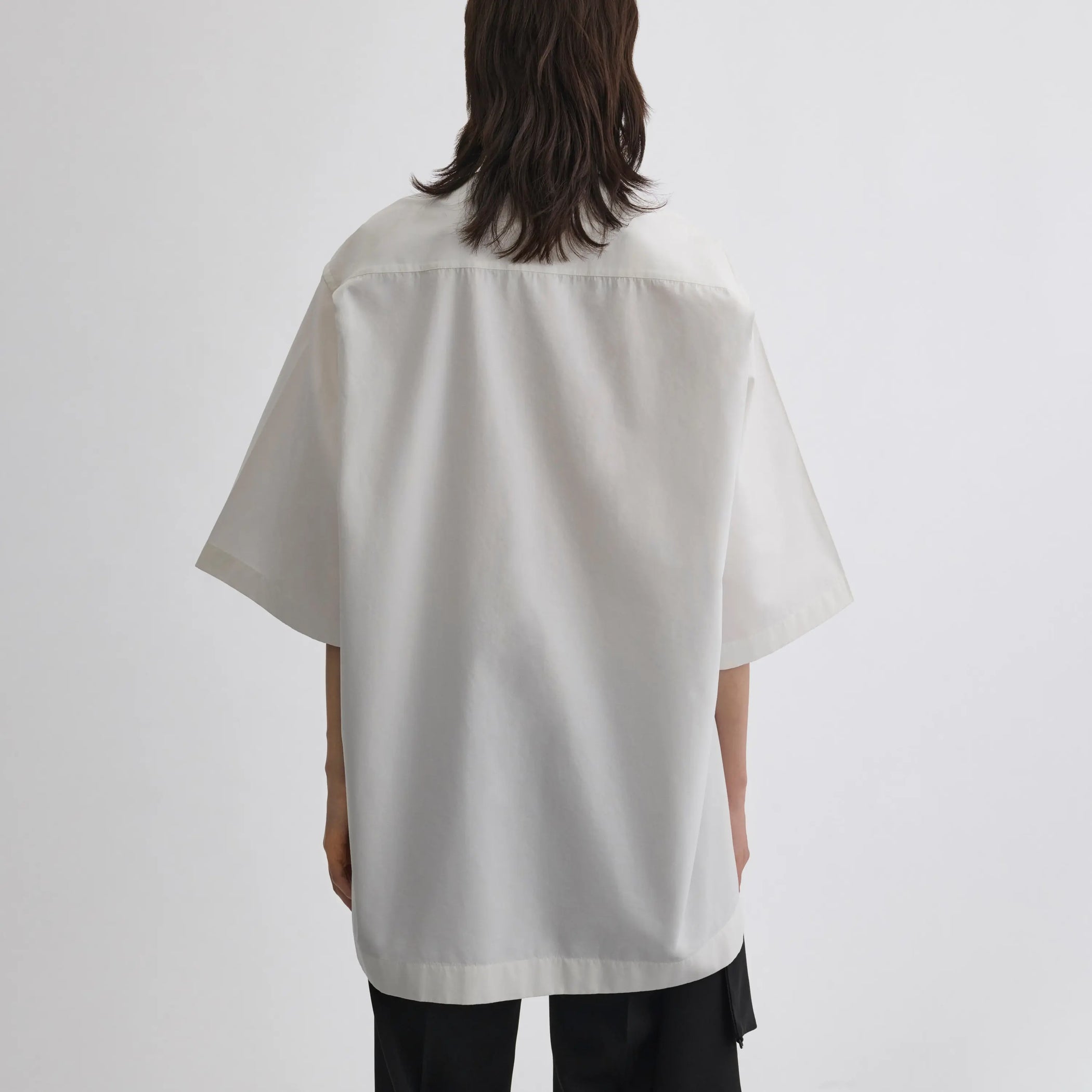 Back view of model wearing UNIFORM SHIRT in white cotton