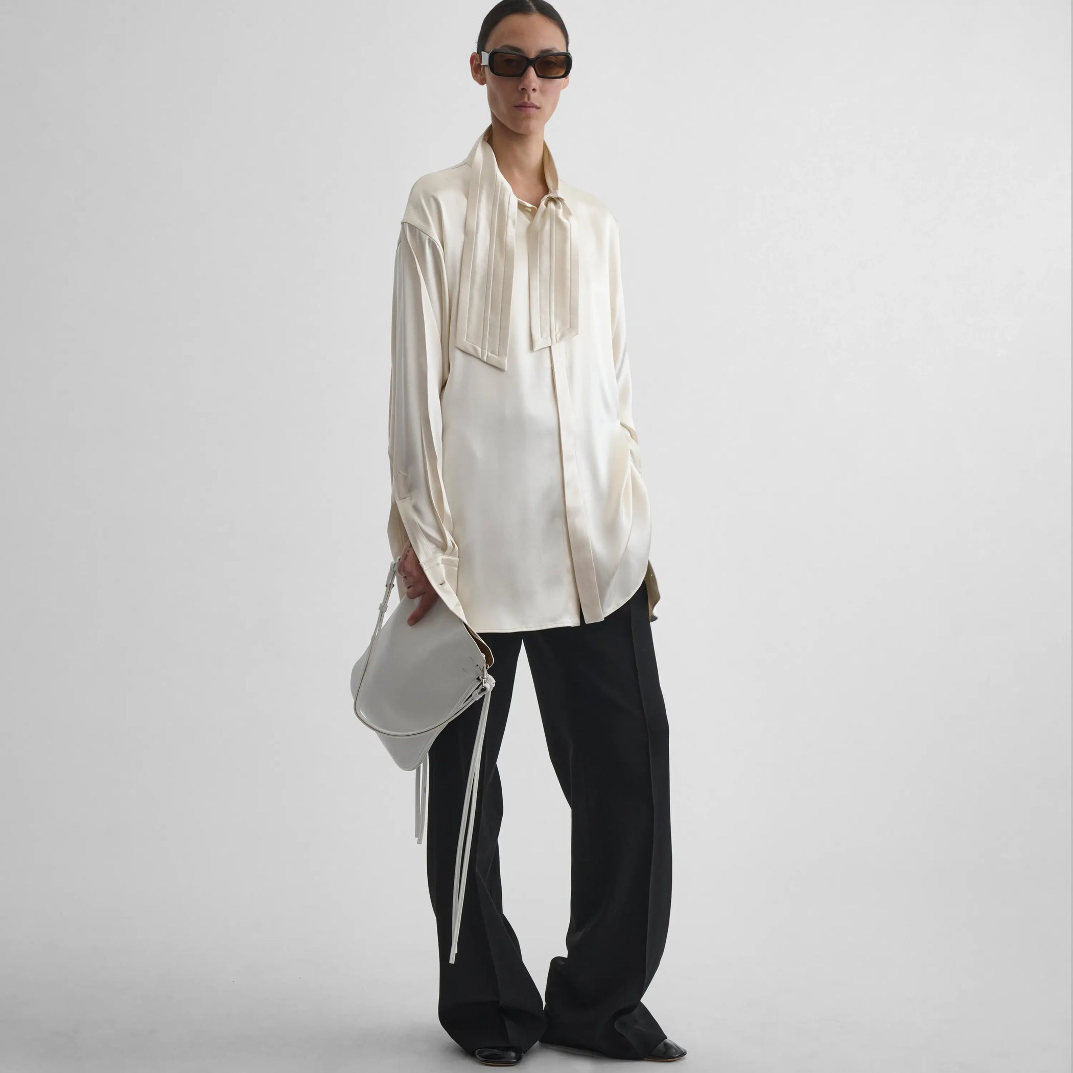 Full body front view of model wearing Tie Neck Shirt in cream.