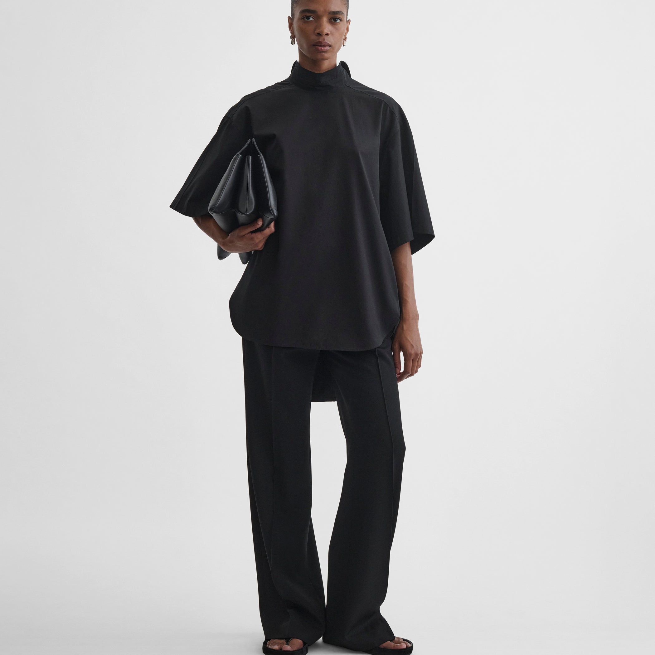 Front full body view of model wearing tie neck short sleeve shirt in black cotton