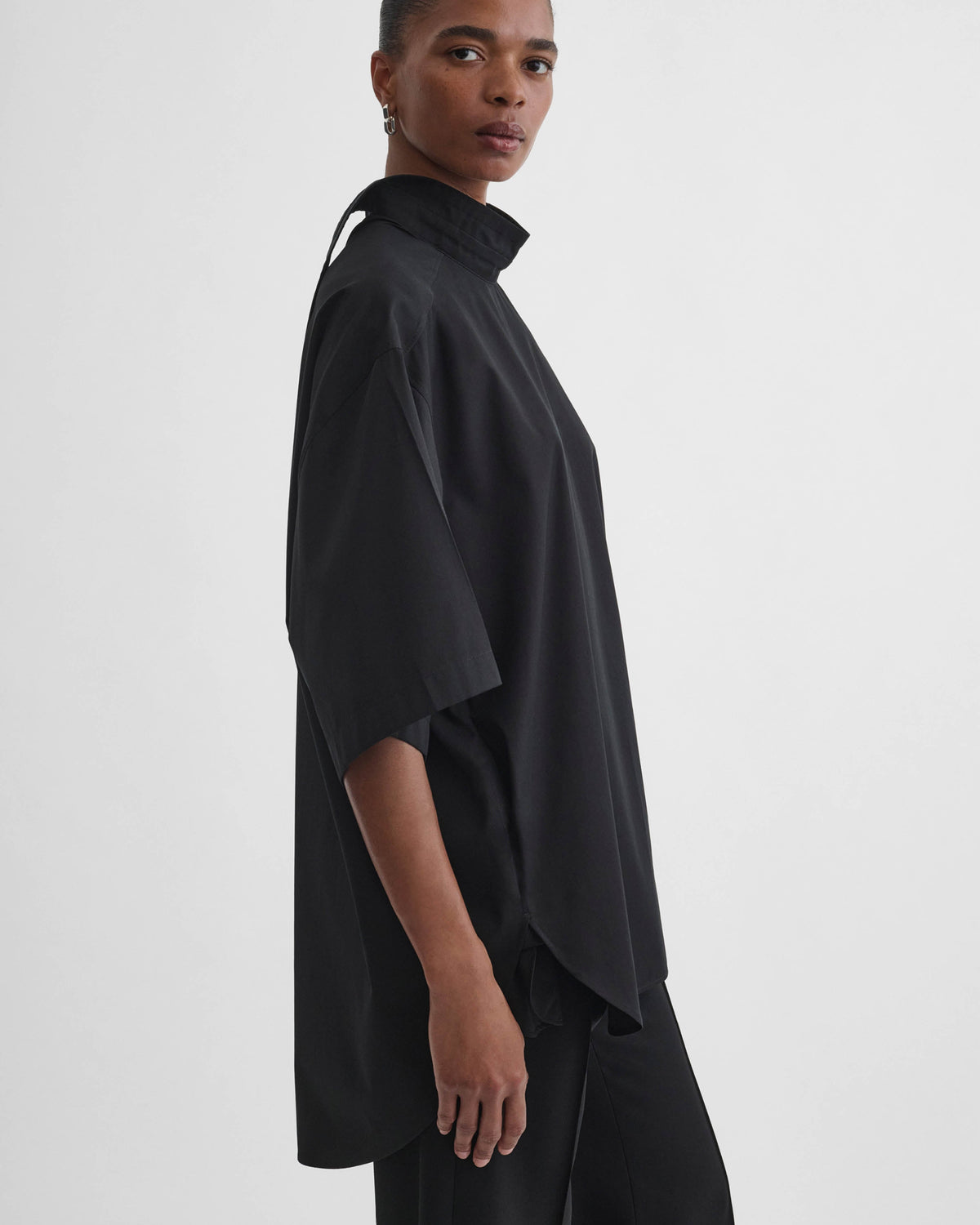 Side view of model wearing TIE NECK SHORT SLEEVE SHIRT in black cotton