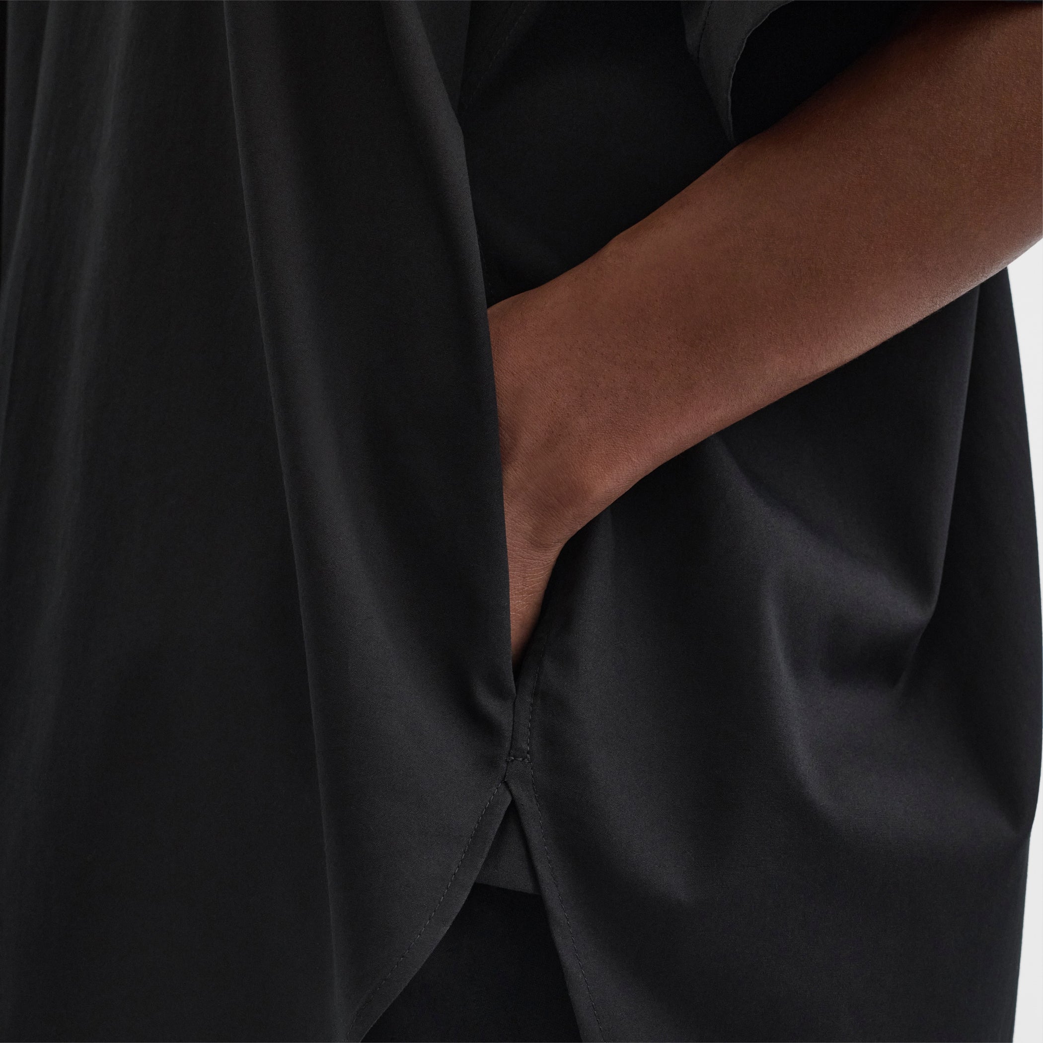 Close up detail view of model wearing tie neck short sleeve shirt in black cotton