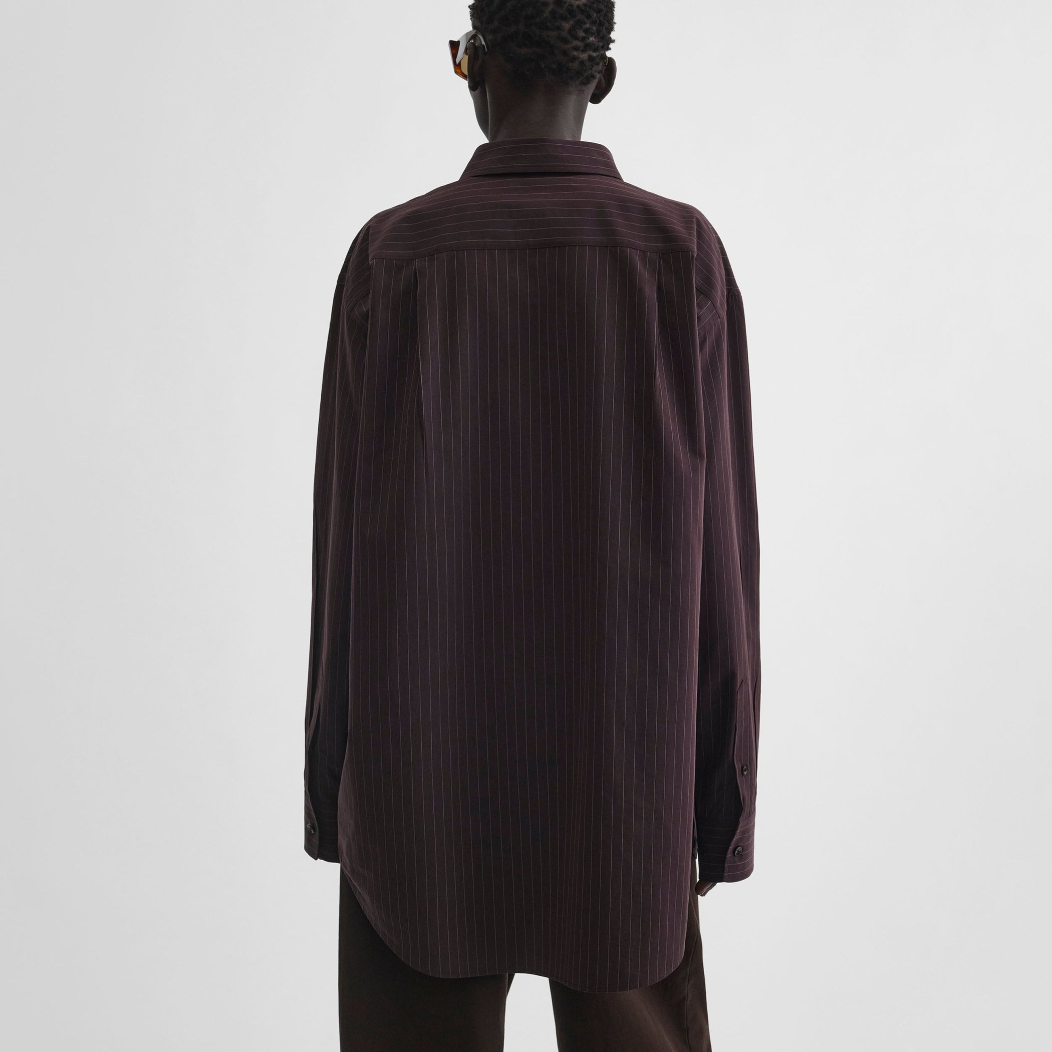 Back view of model wearing sharp collar shirt in black cherry pinstripe cotton