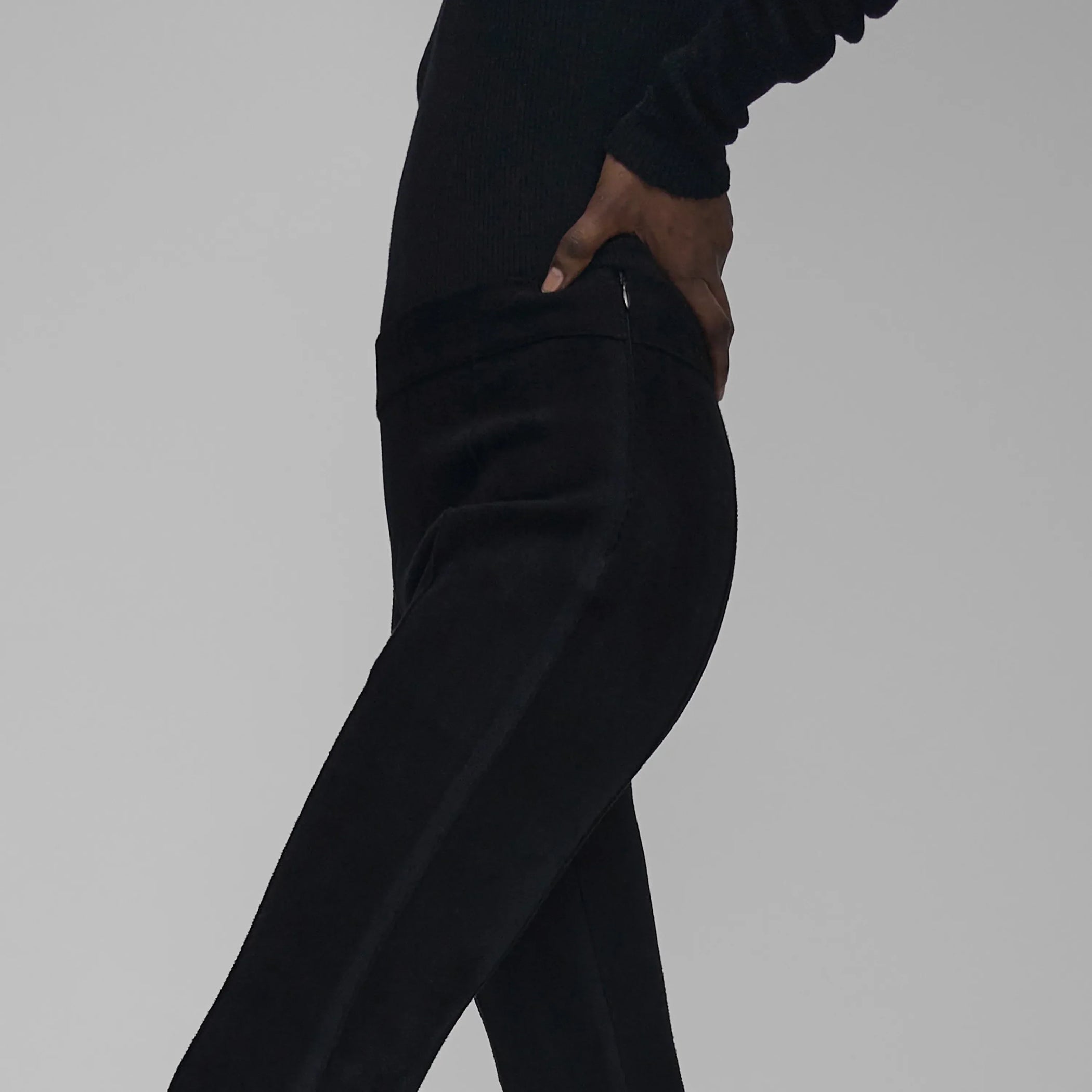 Side detail view of model wearing CHENILLE TROUSERS in black technical polyester