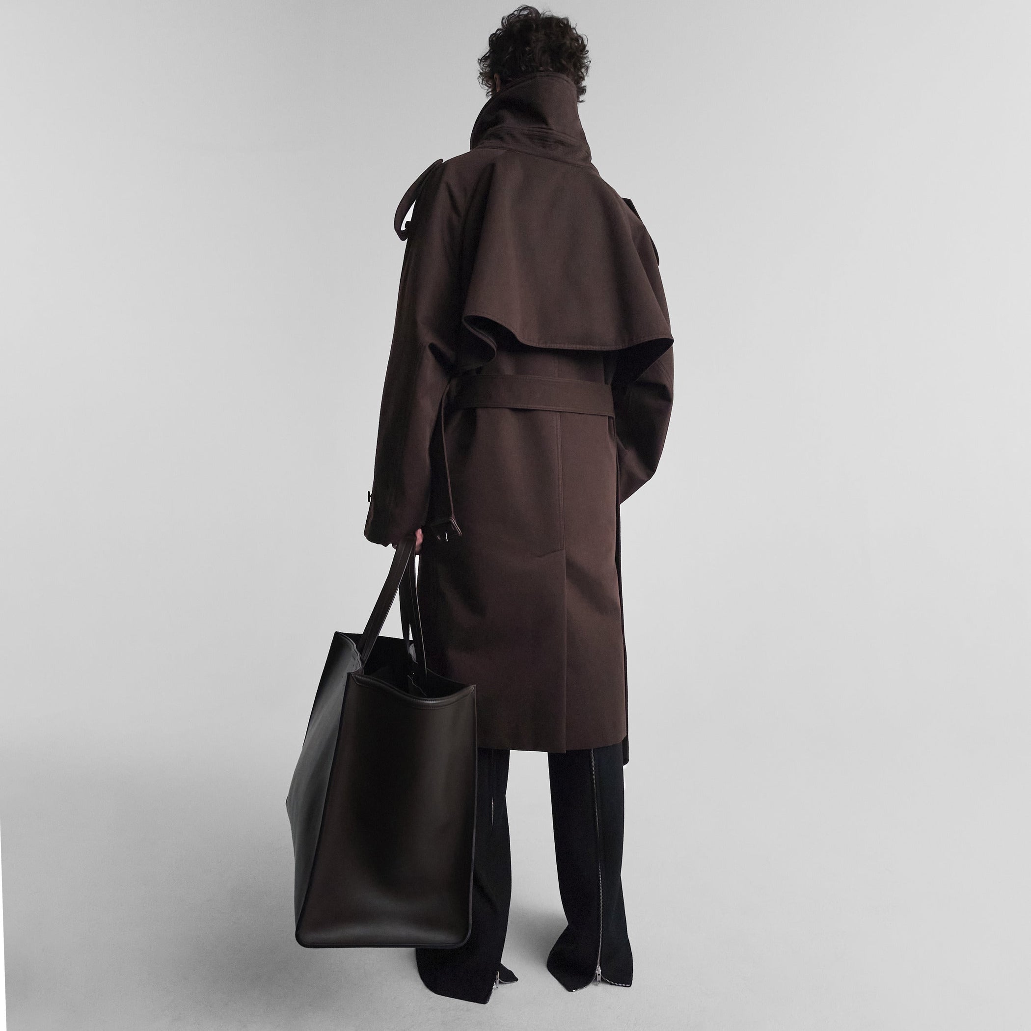 Back view of model wearing PADDED TRENCH COAT in chocolate brown cotton drill