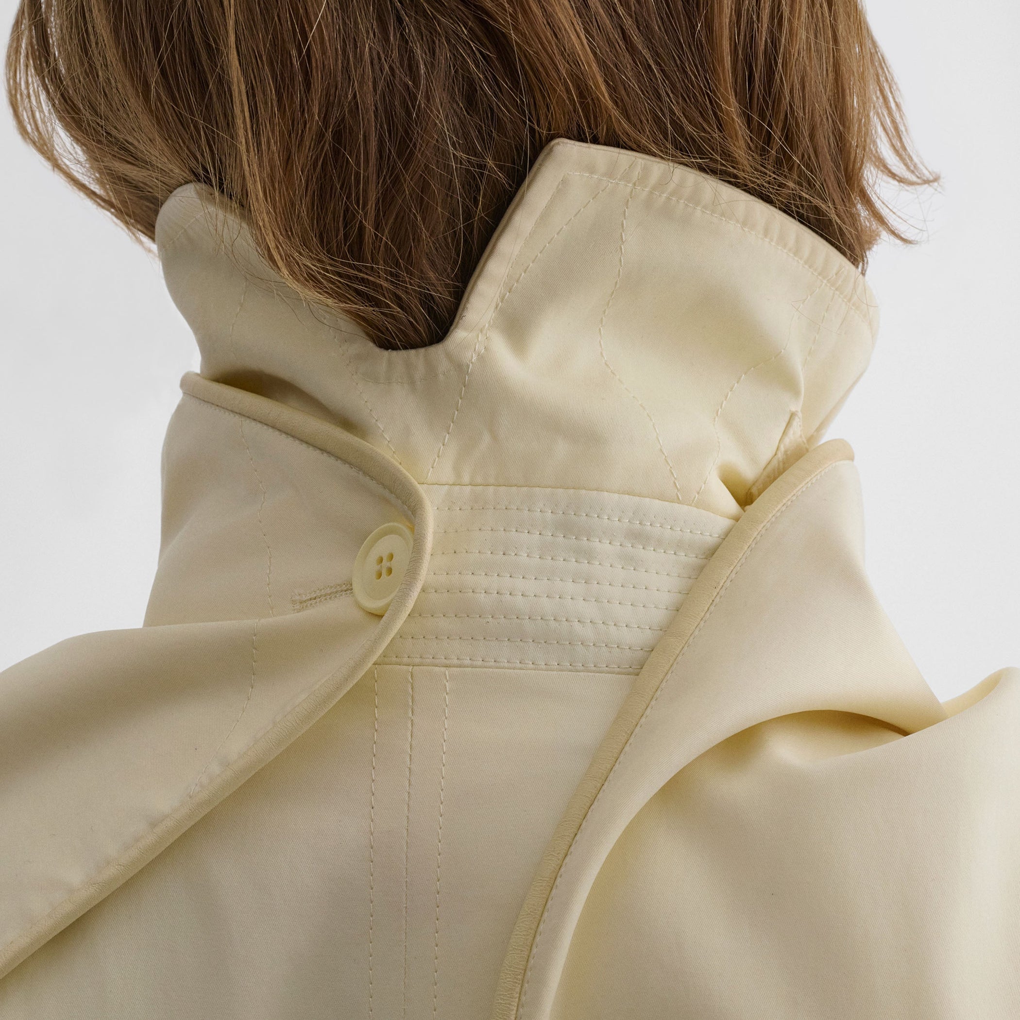 Close up detail view of model wearing TRENCH COAT WITH ATTACHABLE SCARF in cream technical polyester