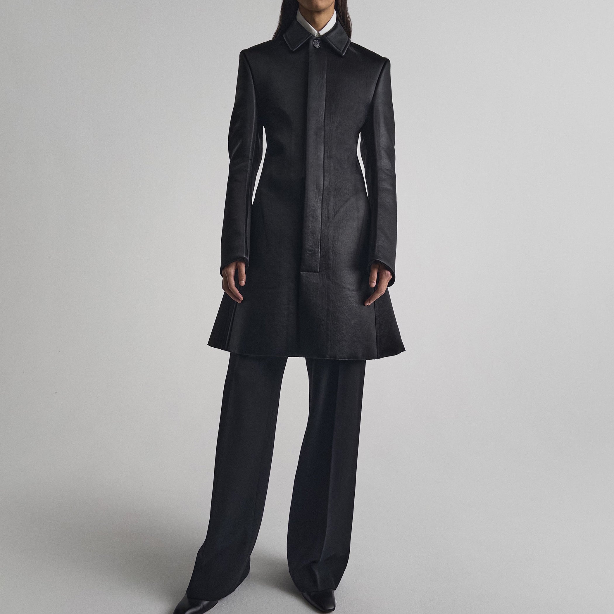 Front view of model wearing SHORT COAT in black bonded satin