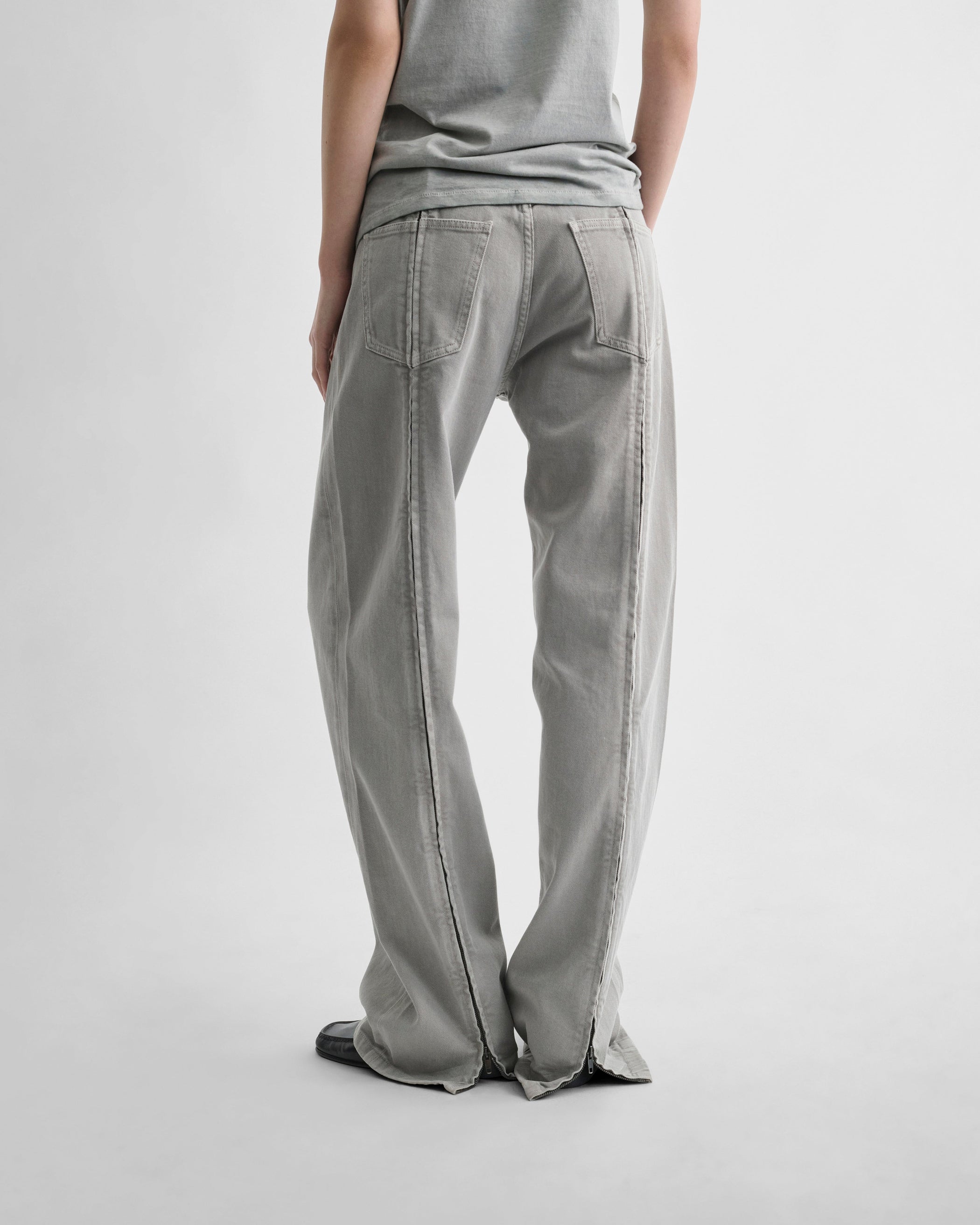 Back view of model wearing ZIP JEANS in ash grey cotton