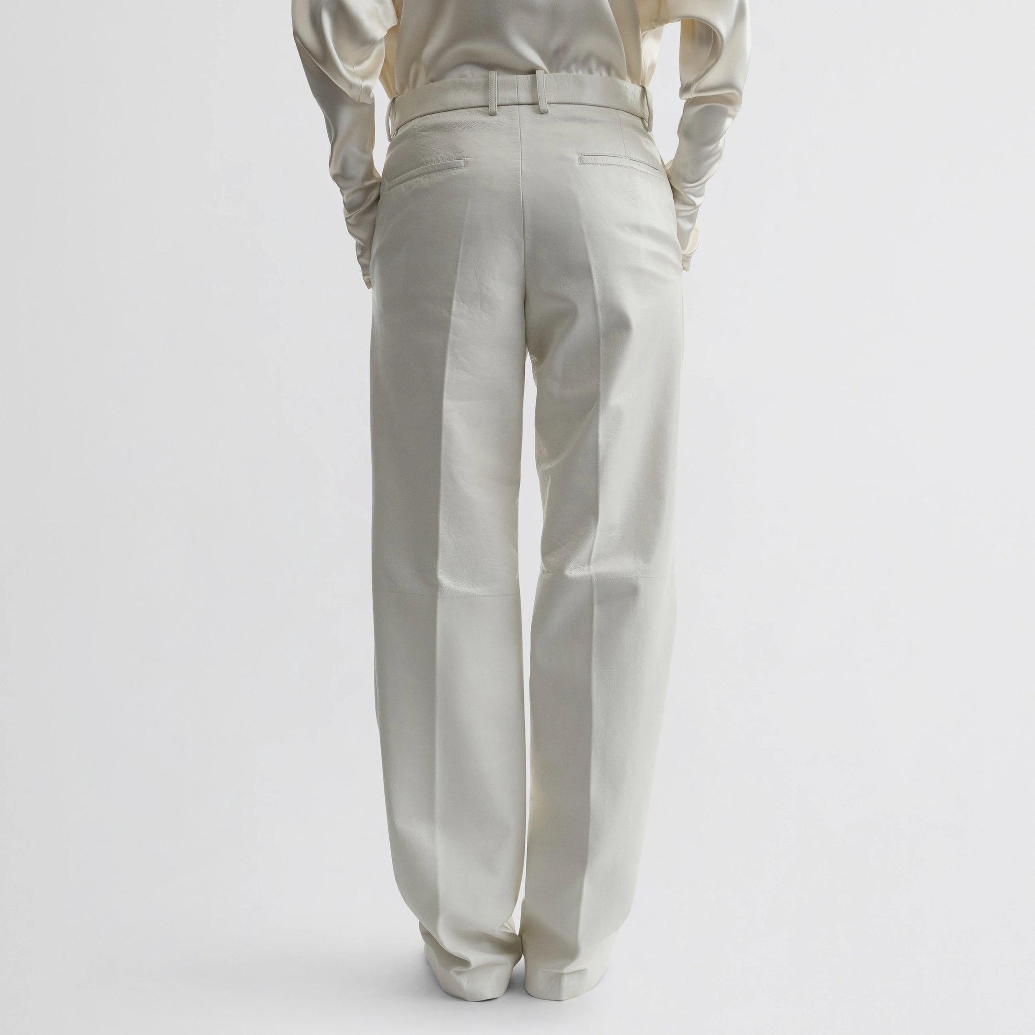 Back view of model wearing boyish trousers in white leather.