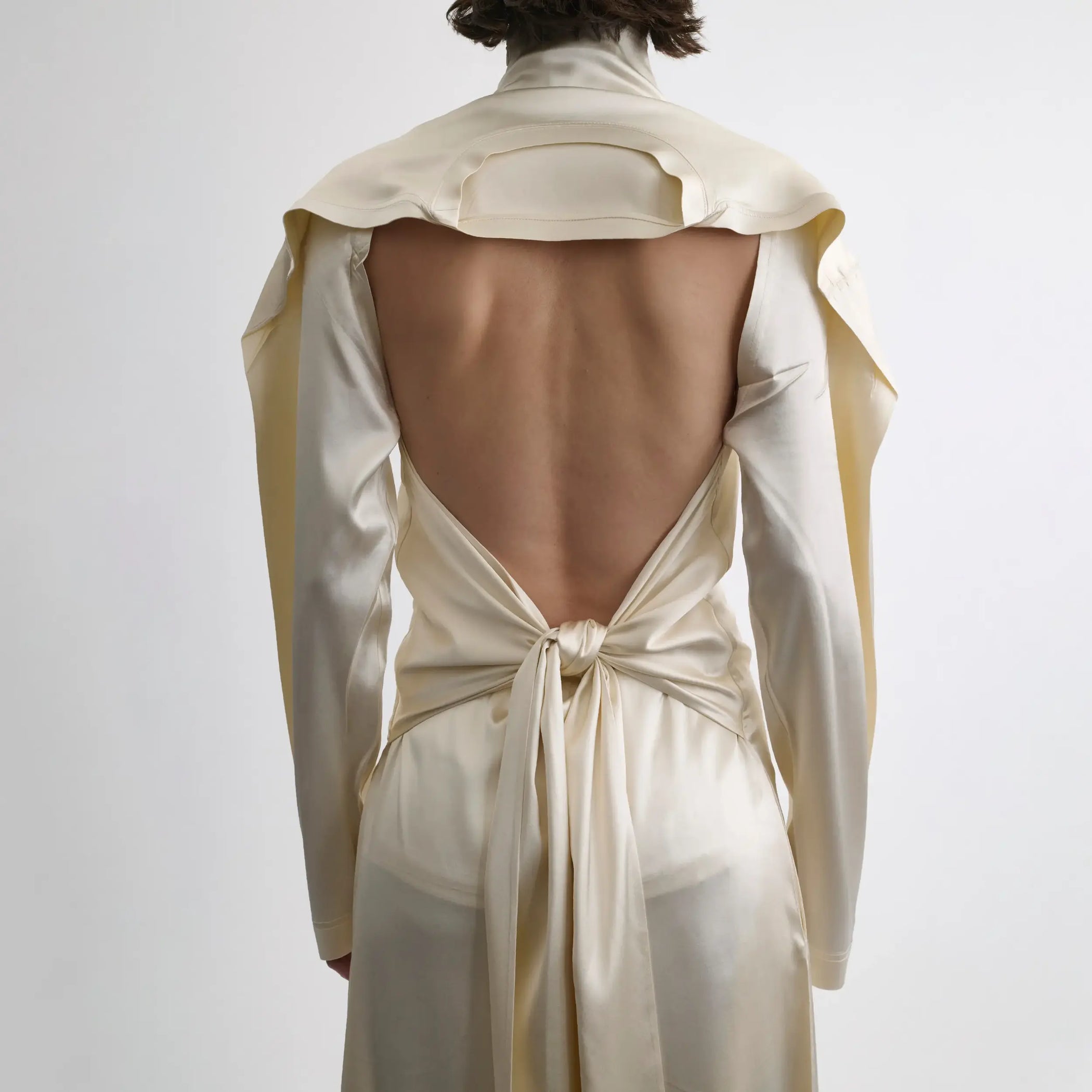 Back view of model wearing LIQUID OPEN BACK DRESS in cream silk satin