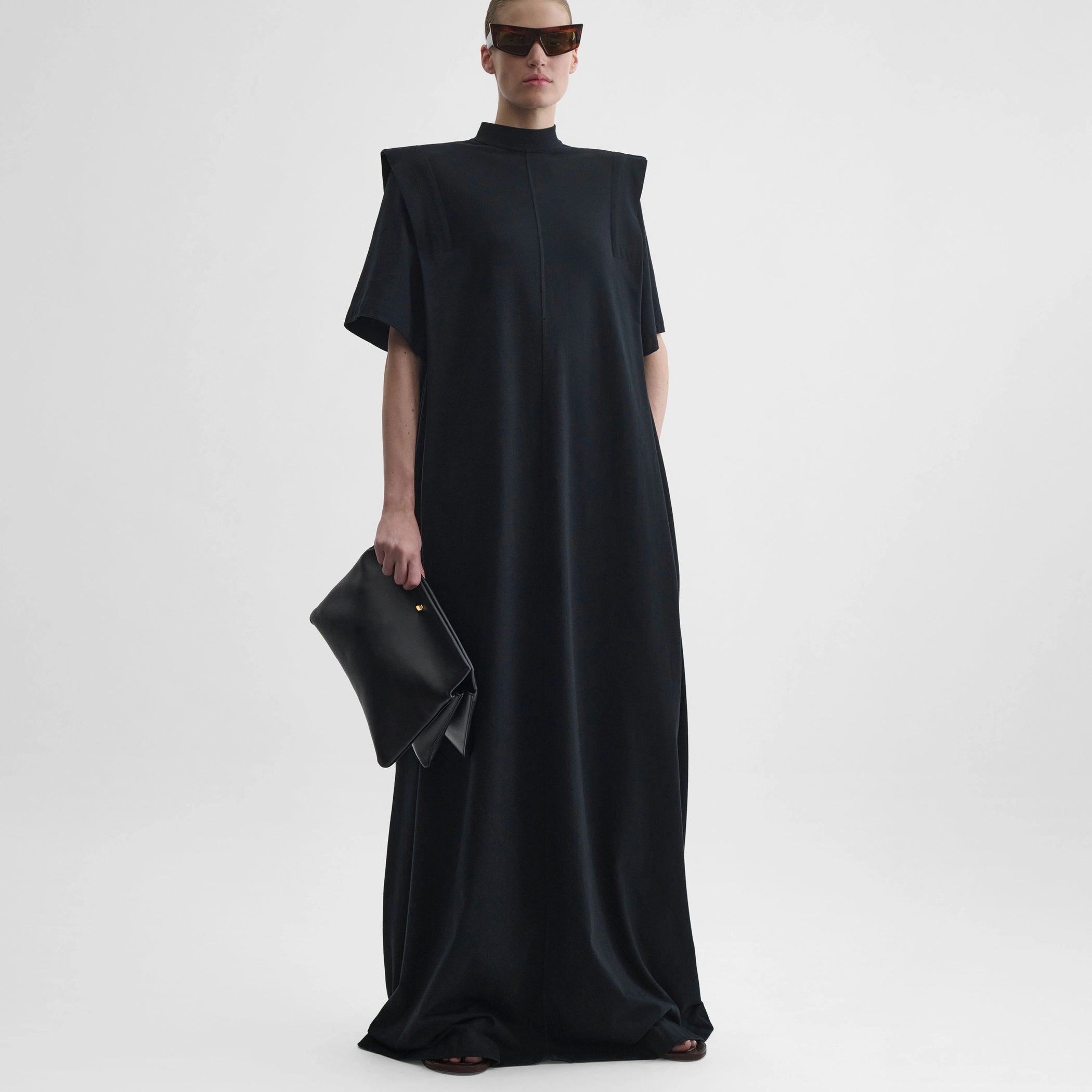 Front full body view of model wearing folded shoulder dress in black jersey
