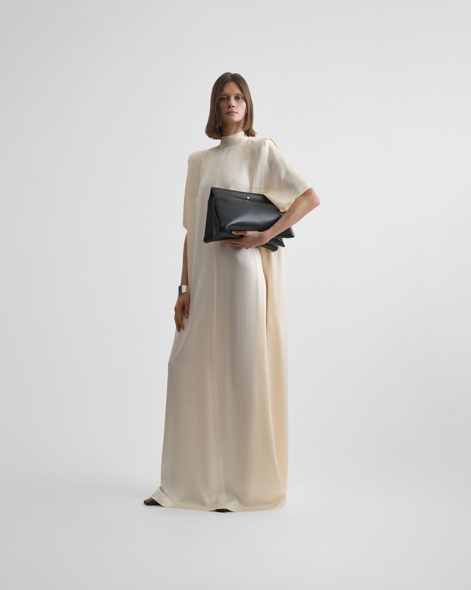 Front full body view of model wearing folded shoulder dress in vanilla satin back crepe