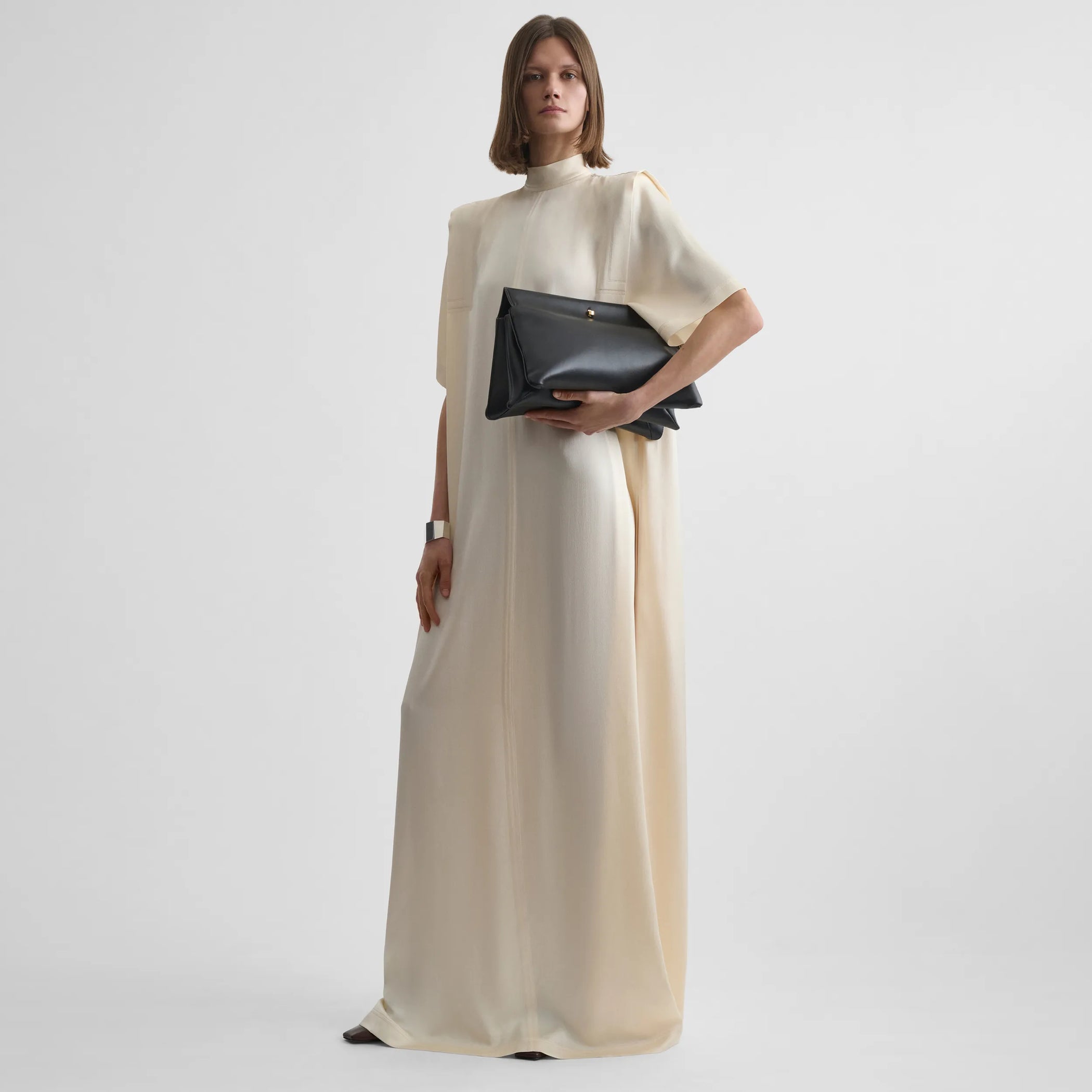 Front full body view of model wearing folded shoulder dress in vanilla satin back crepe